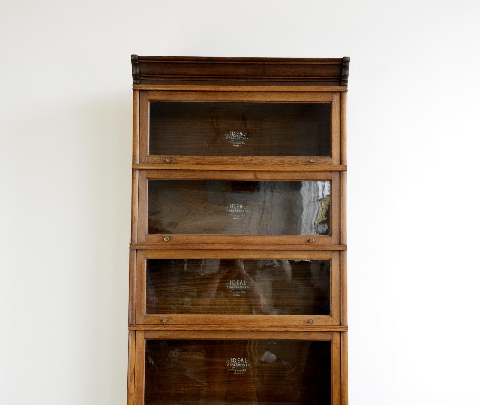 Large early 20th century bookcase by Soennecken

- Solid oak with glass windows
- Each window lifts up and slots in
- Each section is branded with gold lettering and flower detailing
- Brass flower handles
- Comes apart in 8 sections
- Made