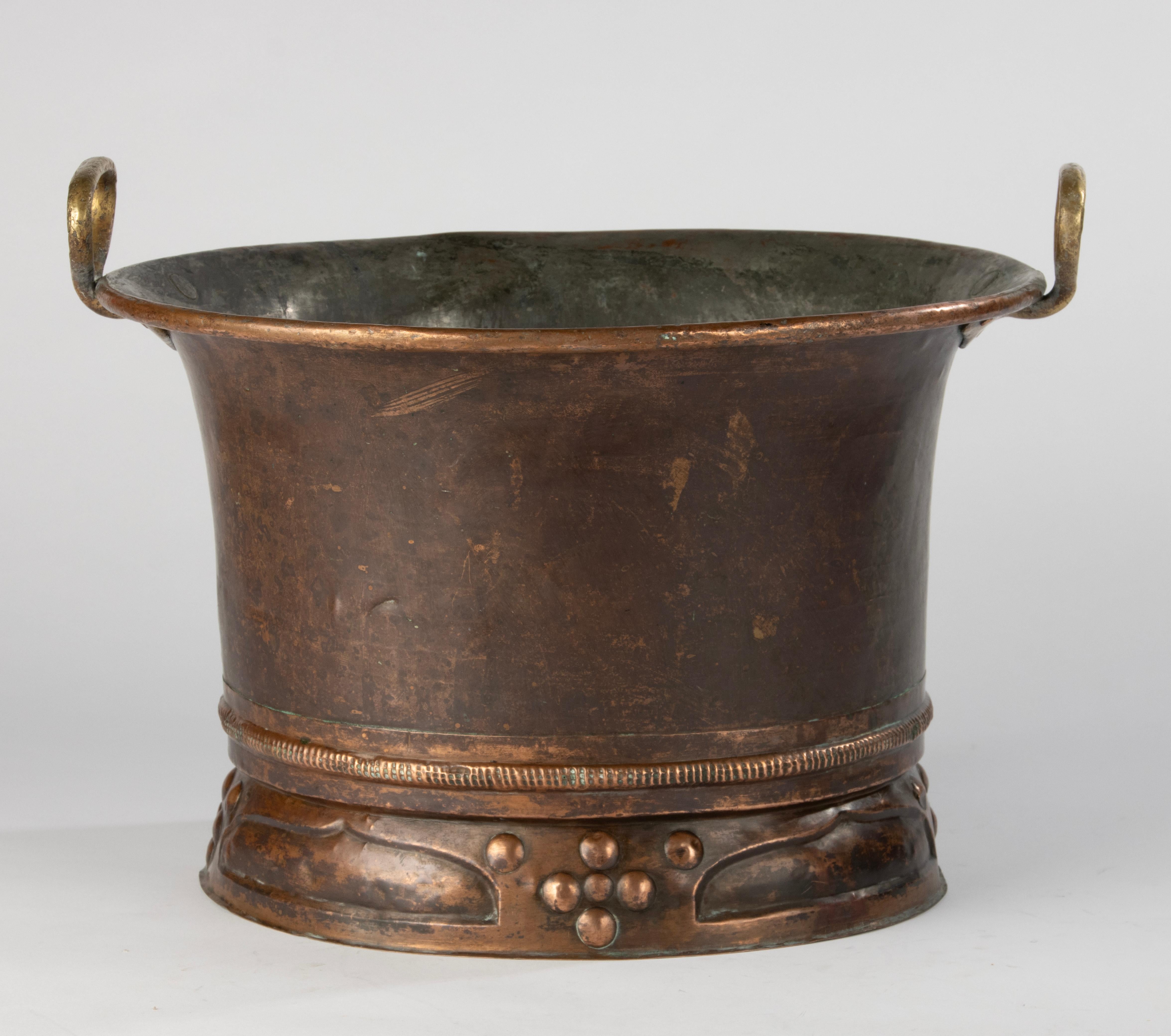 Large and striking French champagne or wine cooler in copper over zinc, dating from around 1900. The piece features beautifully aged patina, a hand-worked decorative base in the Arts and Crafts style, and bold brass handles for easy lifting —