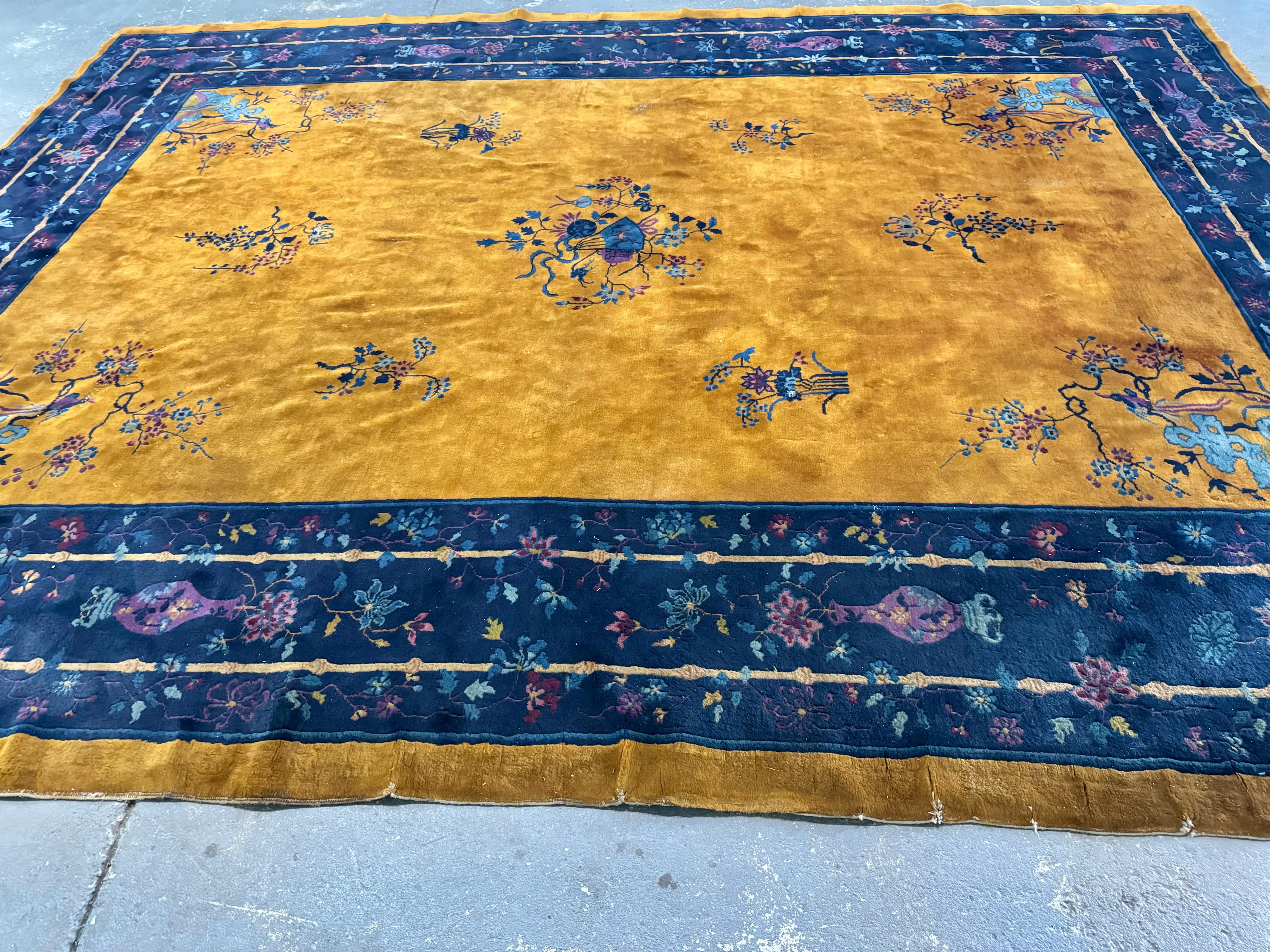 Maravillosa y brillante alfombra Art Decó china de principios del siglo XX, obra de Walter Nichols . con un brillante naranja dorado  campo central rodeado de un amplio borde añil, y todo ello superpuesto con una miríada de flores que incluyen
