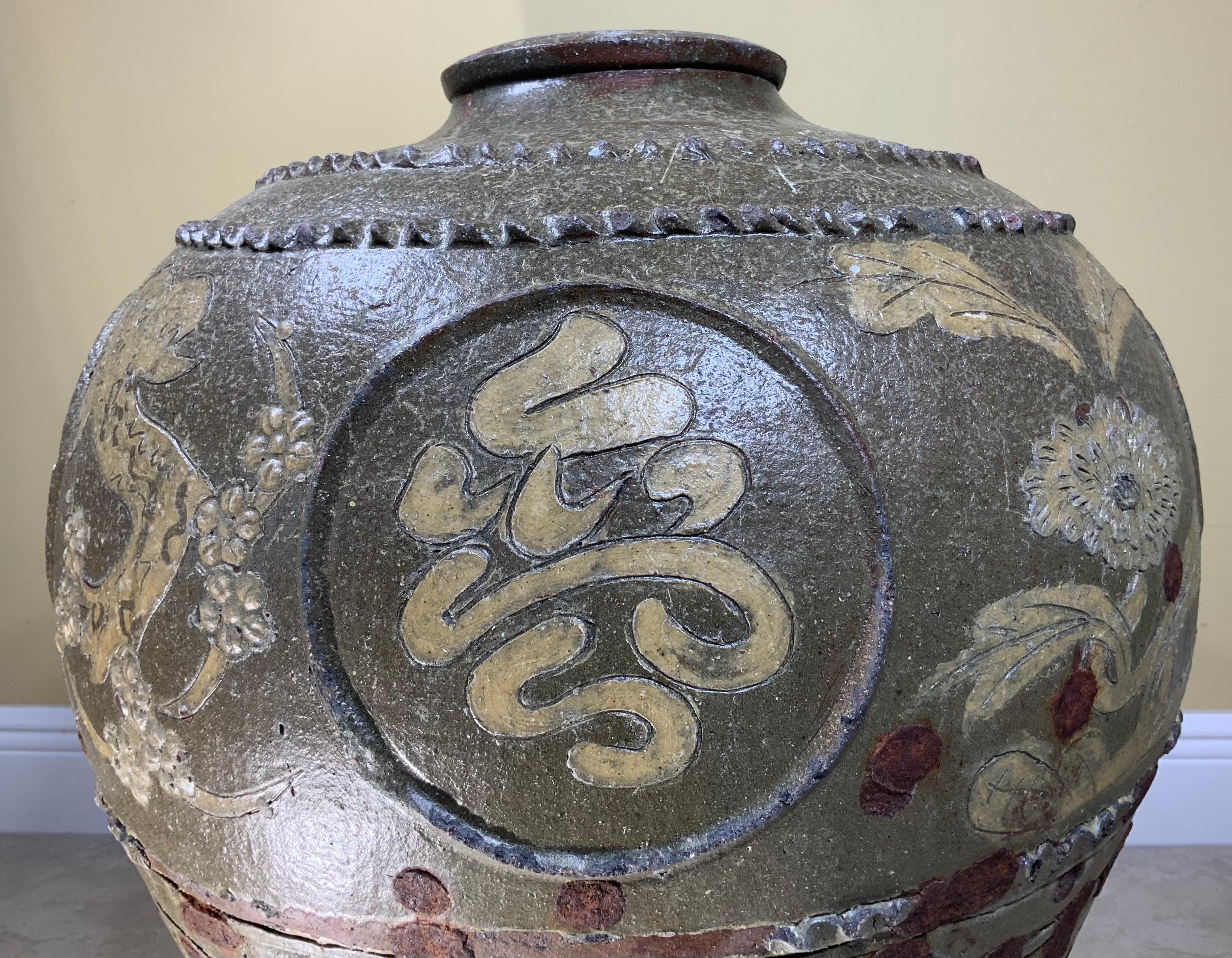 This jar made by hand with exceptional floral and Chinese calligraphy motifs marked on it, and beautifully glazed with olive color.
The unique look in this jar show as that while in the process of making the jar, the artist add some pieces of metal