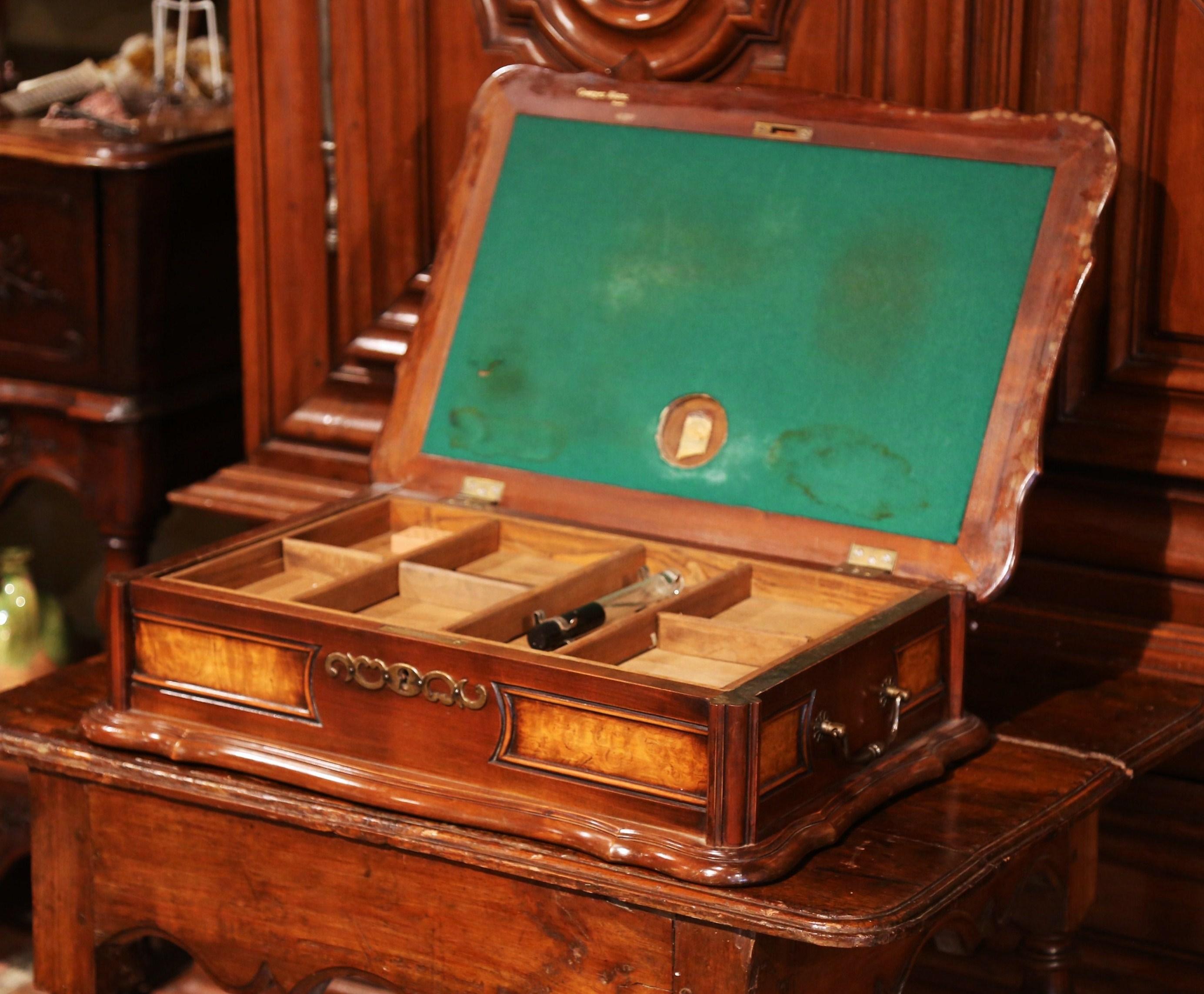 Offer your guests a cigar in style with this antique humidor! Crafted in France by Georges Blanc circa 1920, the two-tone fruitwood cigar box is made of walnut and burl and has sturdy iron handles. When you lift the top, the box reveals a green felt