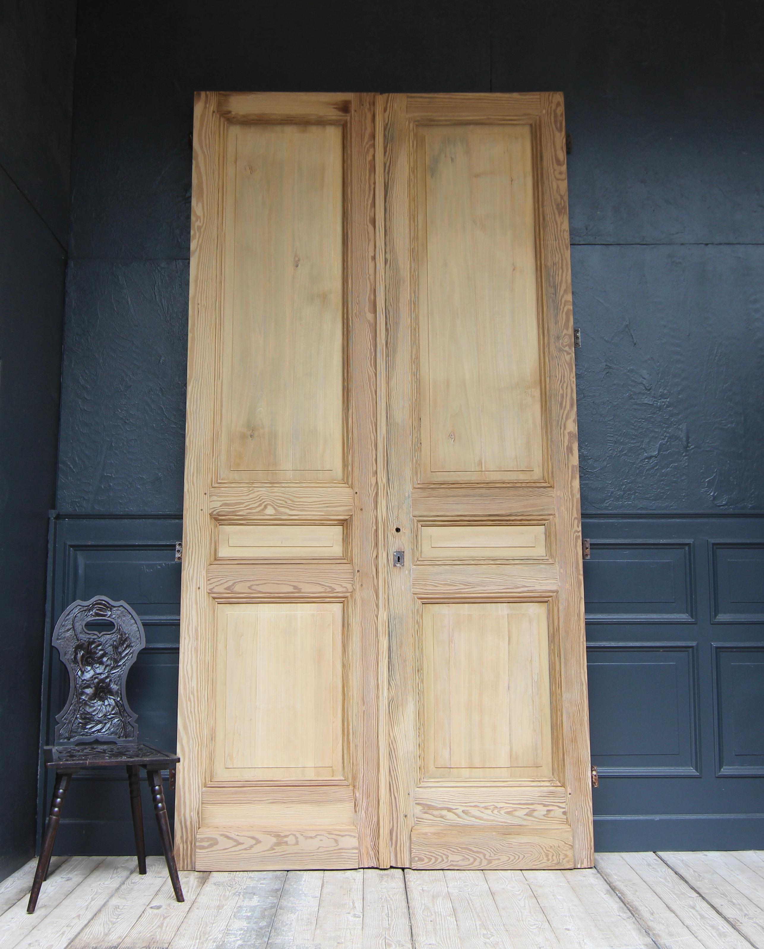 Exceptionally high French double door from the early 20th century, probably around 1910. Solidly made of pine.

Double-leaf residential door in frame construction with 3 panelled panels per door leaf.

The double door can be installed with 4 iron
