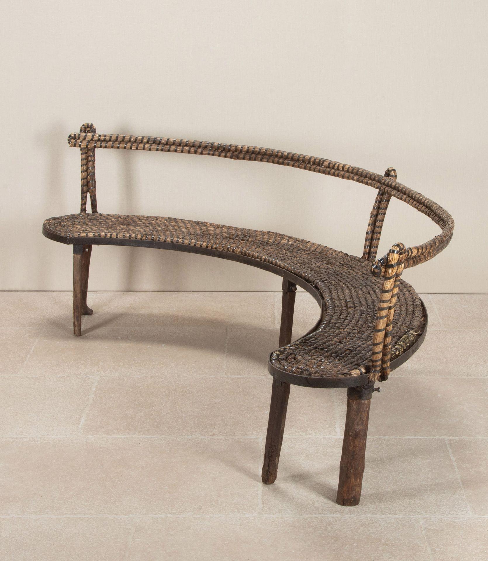 Unique et original, ce grand banc en bois demi-lune français du début du 20e siècle. L'assise en paille rustique entrelacée repose sur un cadre en fer incurvé soutenu par six pieds en chêne fendus, boulonnés et amovibles. Les trois jambes à l'avant