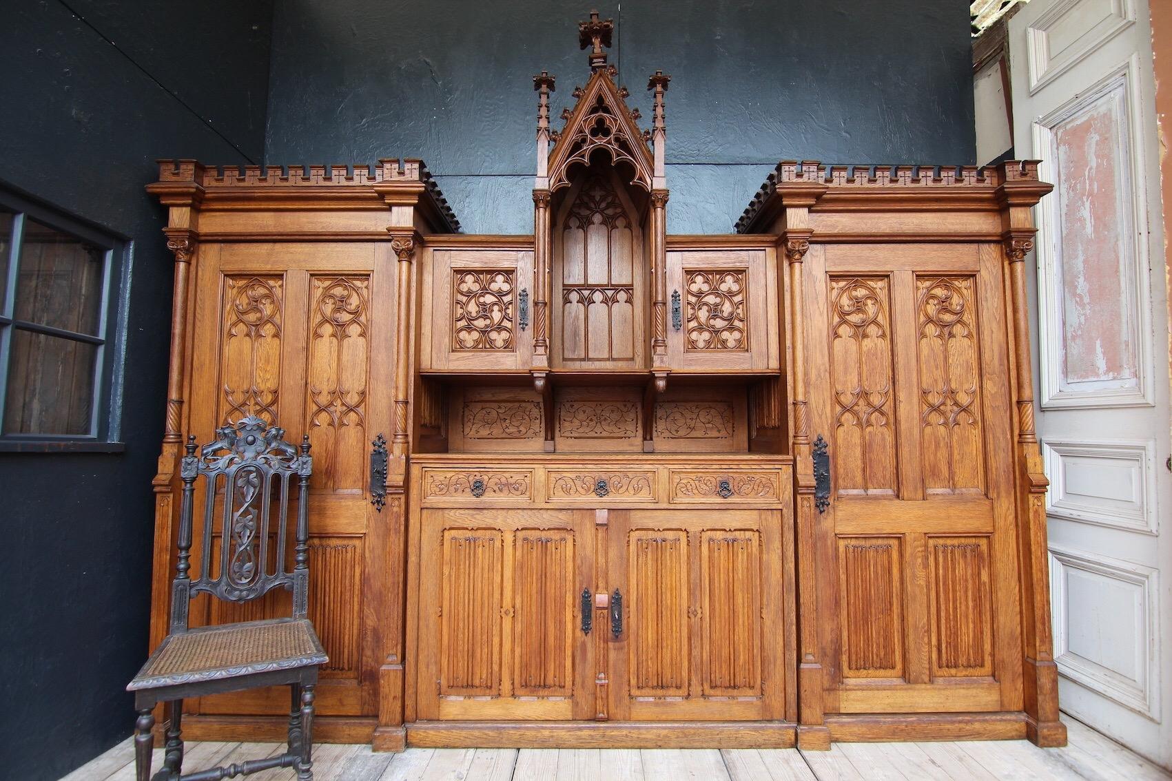 A Gothic Revival sacristy cabinet from the 1920s/30s. The piece of furniture comes from the sacristy of the Brandts Chapel of St. Aloysius in Mönchengladbach.

High-quality oak wood. Richly decorated and carved.

The cabinet consists of a central