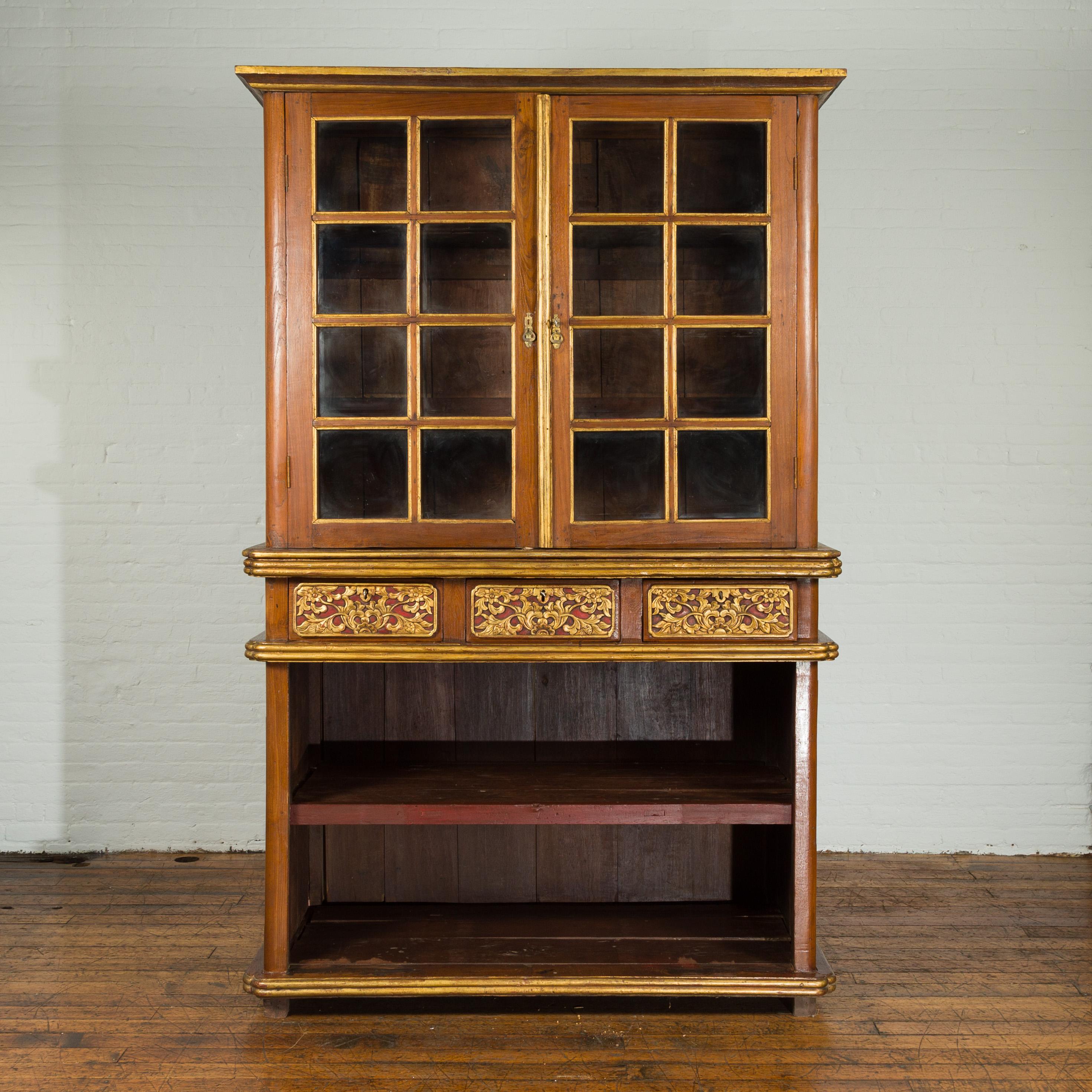 Un grand cabinet indonésien du début du 20e siècle avec des portes en verre biseauté et trois tiroirs. Créée en Indonésie au début du XXe siècle, cette grande armoire comporte deux portes en verre à panneaux dans sa partie supérieure, qui s'ouvrent