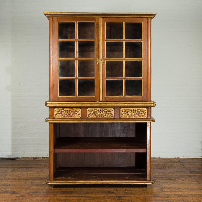 A large Indonesian cabinet from the early 20th century with beveled glass doors and three drawers. Created in Indonesia during the early years of the 20th century, this large cabinet features two paneled glass doors in its upper section, opening to