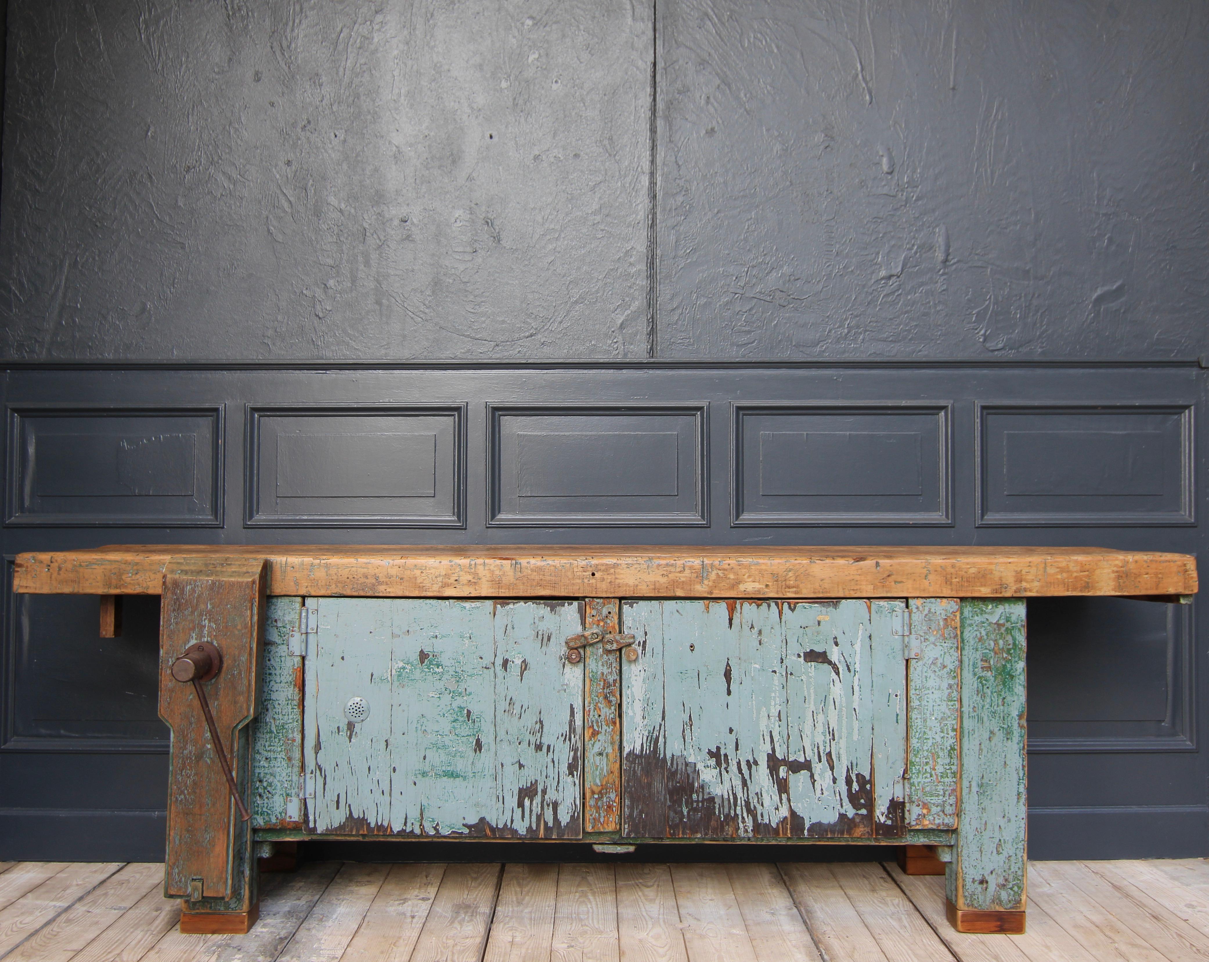 Large vintage workbench from the 1st half of the 20th century. Made of solid beech and pine wood. 

Two-door base cabinet with original patina and large vice at the front left. On top the solid beech wood worktop.

Dimensions: 
80.5 cm high / 31.69