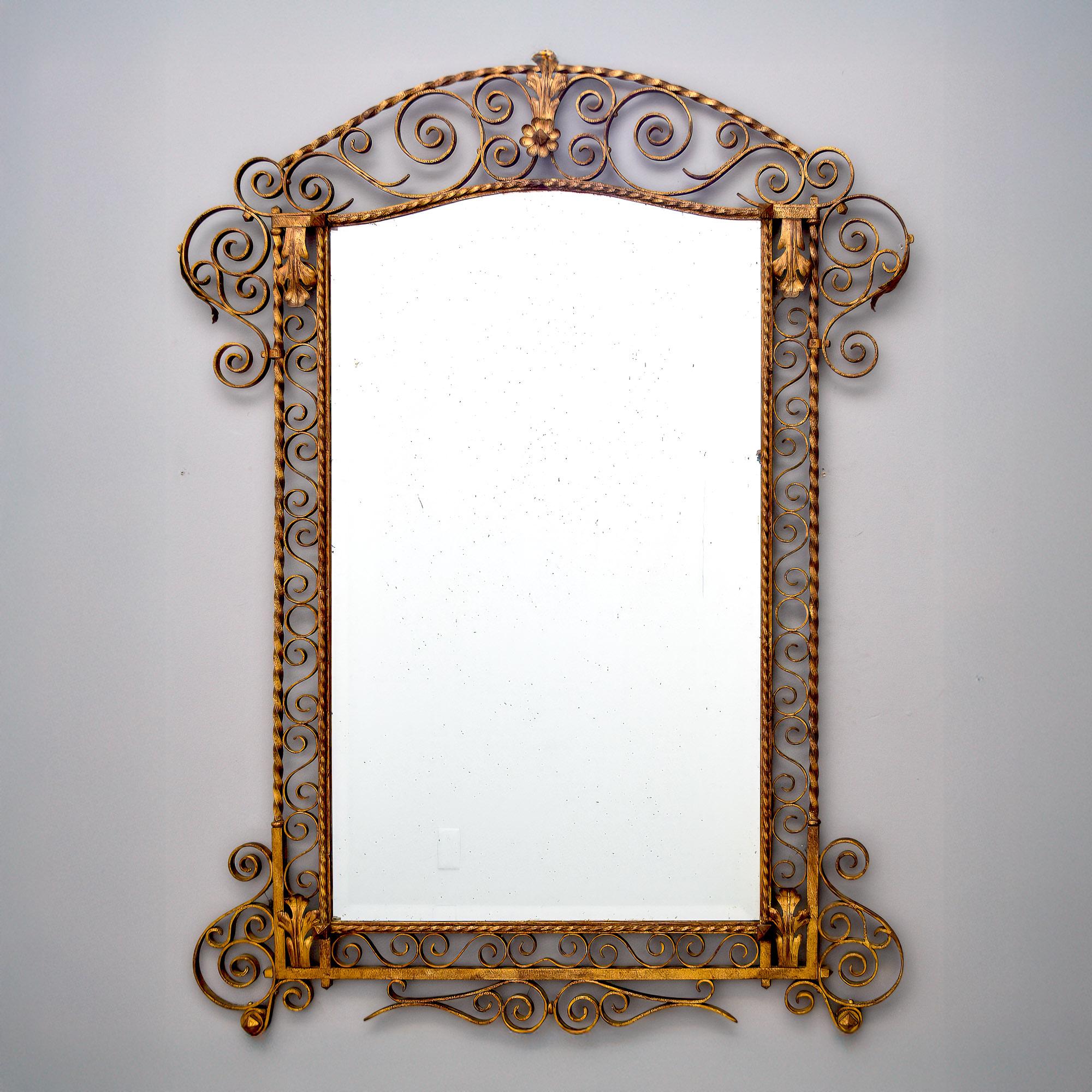 Trouvé en Italie, ce miroir datant des années 1930 a un cadre en fer doré avec de nombreuses volutes décoratives et des accents de feuilles d'acanthe en laiton. Le miroir a un bord biseauté. 
Taille réelle du miroir :  41
