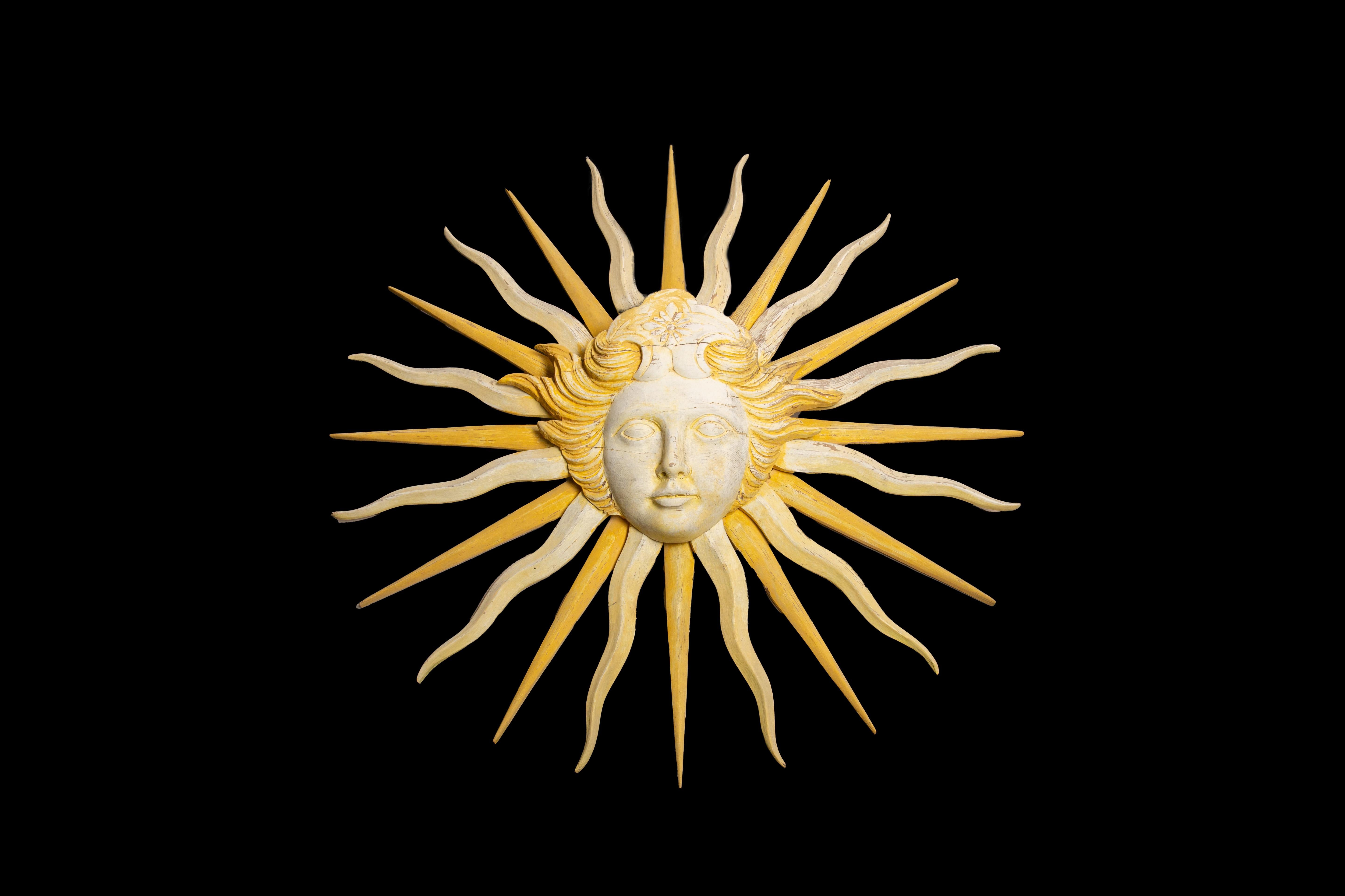 Large Early 20th century Sun King Hand Carved Painted Wood Emblem Sculpture. This magnificent wall hanging captures the elegance and grandeur of the Sun King era. It is hand carved from wood with intricate details and hand painted in vibrant yellow