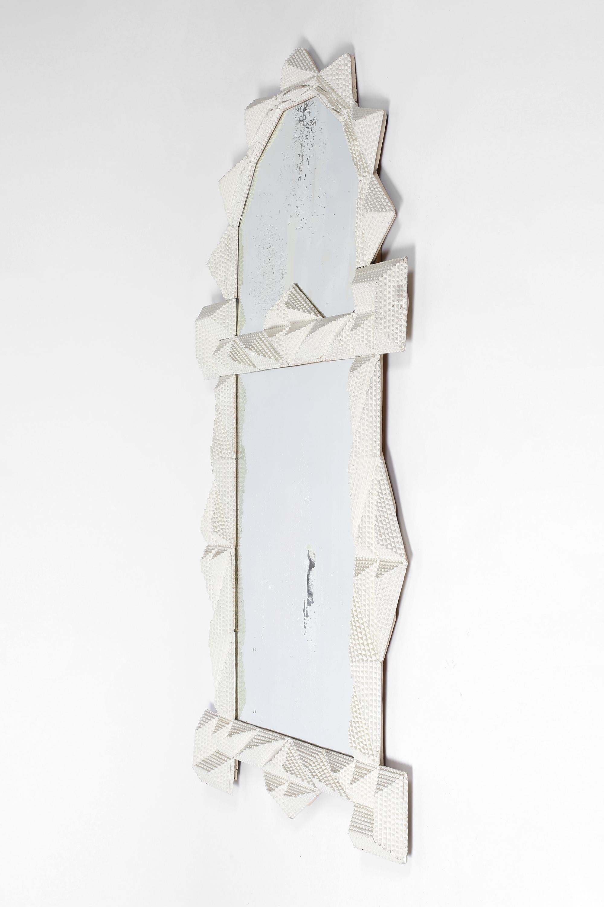 A monumental early 20th century ‘tramp art’ wall mirror - the extravagant frame later painted white, with its original attractively foxed plate. English, c. 1920.

Note: Small crack to the top plate as photographed, does not detract.