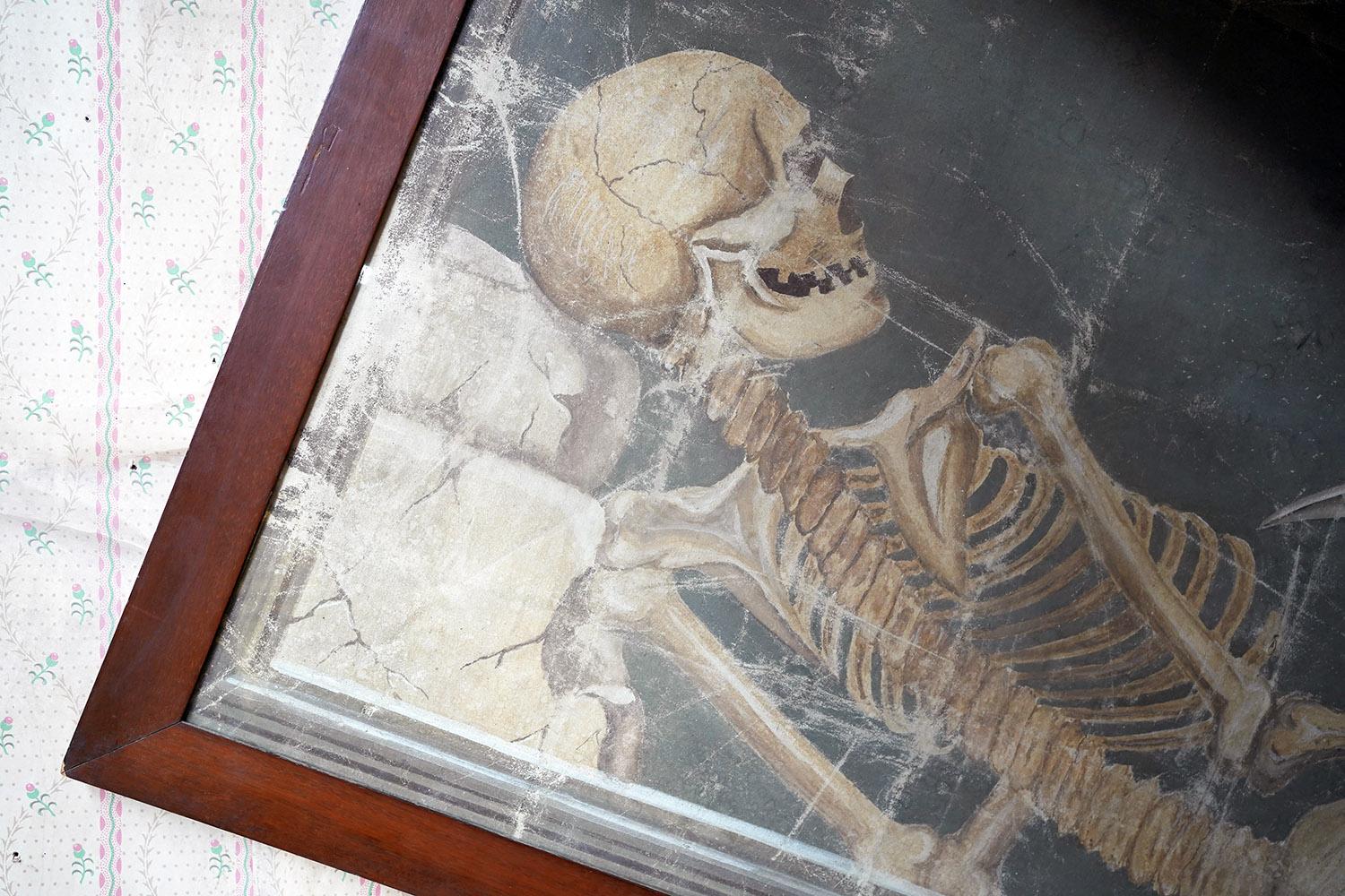 The dramatic and large oil on canvas painting depicting a full skeleton resting upon a monument, holding an hourglass and scythe, painted in profile to a slate ground, and mounted in a walnut frame the whole being glazed and surviving from the first