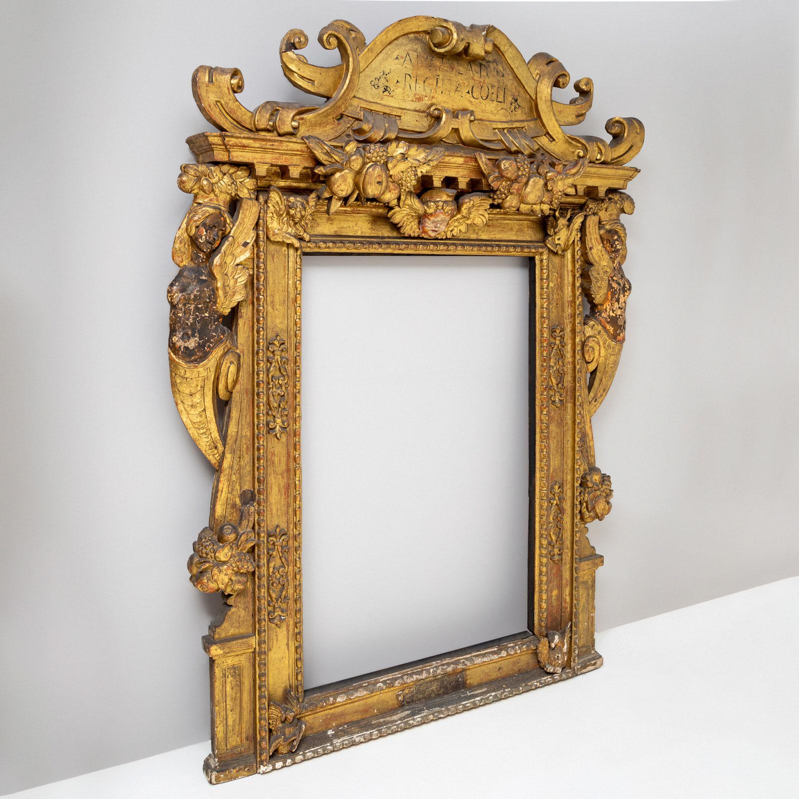 Gran marco barroco dorado de madera tallada con aplicaciones de estuco, parcialmente policromado.
Dimensiones interiores: 116 x 78 cm
El marco, alto y rectangular, está coronado por una gran cartela con volutas entrelazadas y la inscripción 