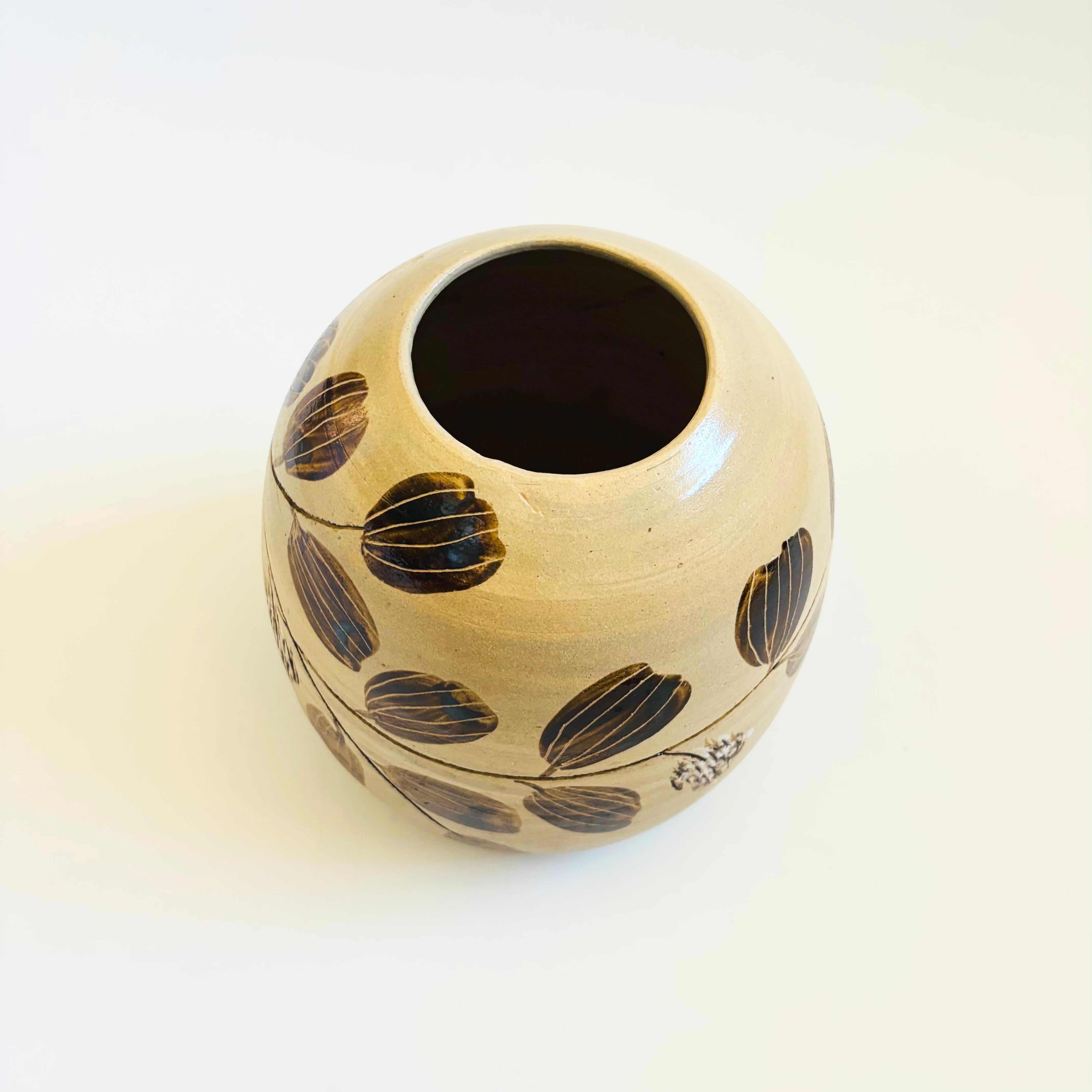 A beautiful vintage hand made pottery vase. Brown and tan glazes with carved and painted leaf design around the sides. Versatile size and shape. Signed by the ceramicist on the bottom.

