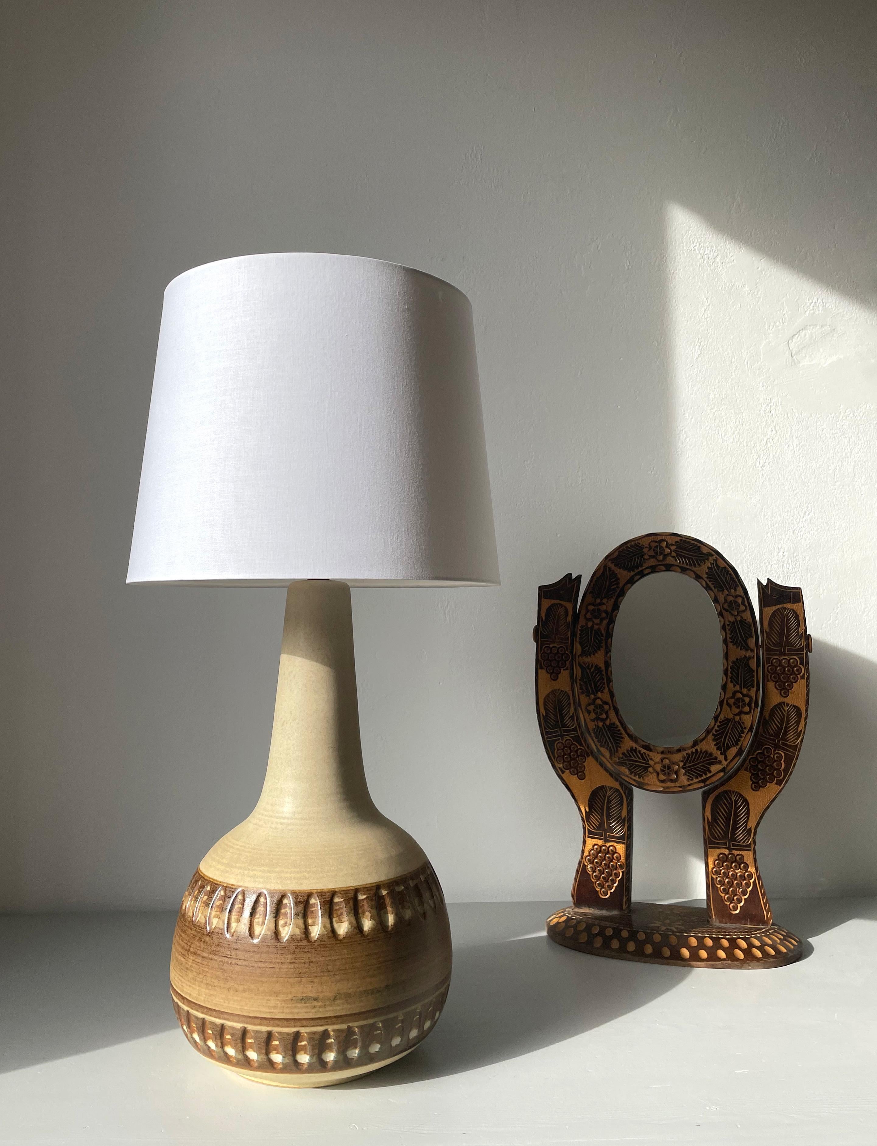 Large sand, beige, brown glazed stoneware lamp manufactured on the Danish island of Bornholm by Søholm Stentøj in the 1960s. Slender light sand colored neck and a brown belly with graphic relief pattern. Fully glazed. Stamped under base. Shade not