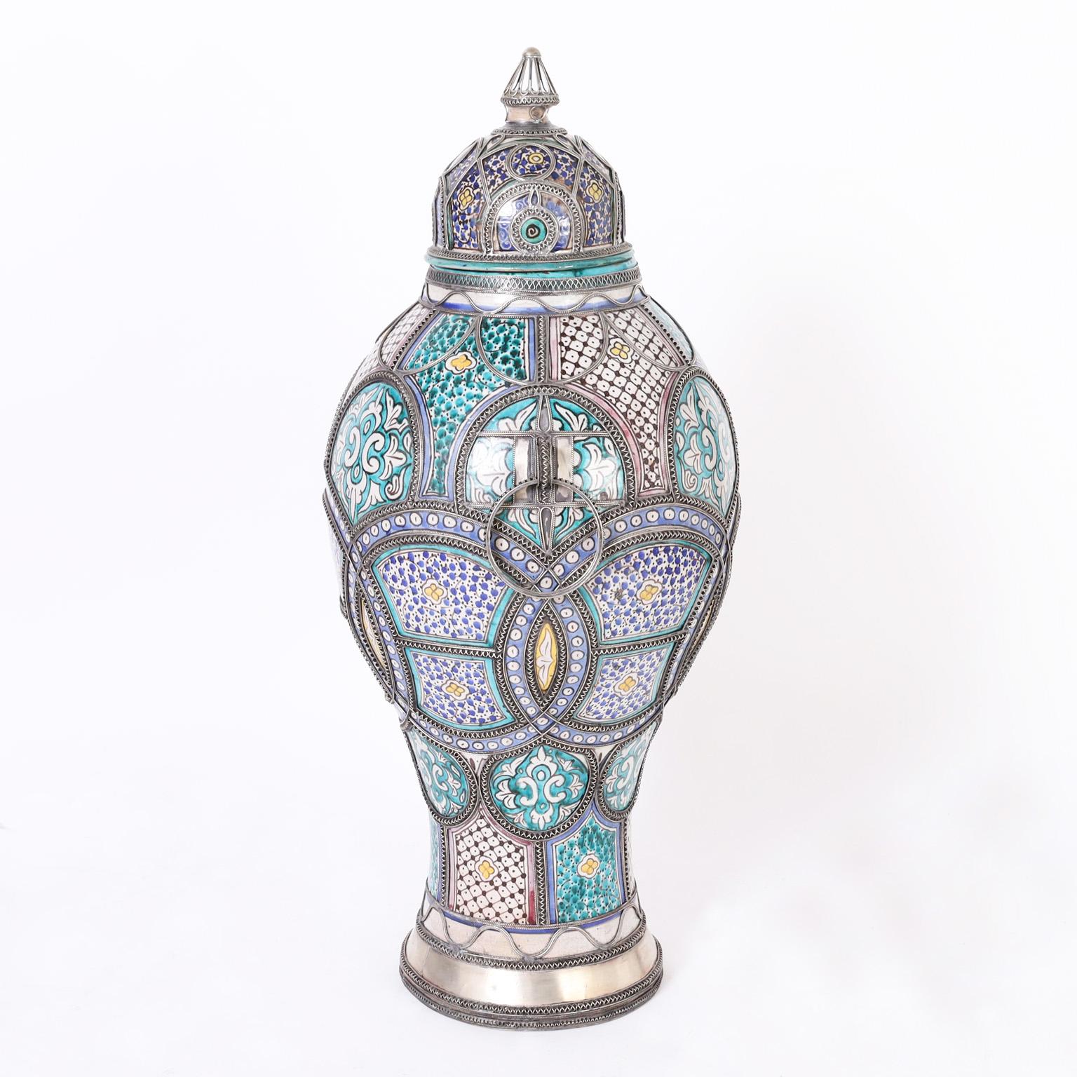 Large and impressive Moroccan lidded urn crafted in terra cotta, glazed over mediterranean colors and decorated with jewelry like metal work that ups the wow factor.