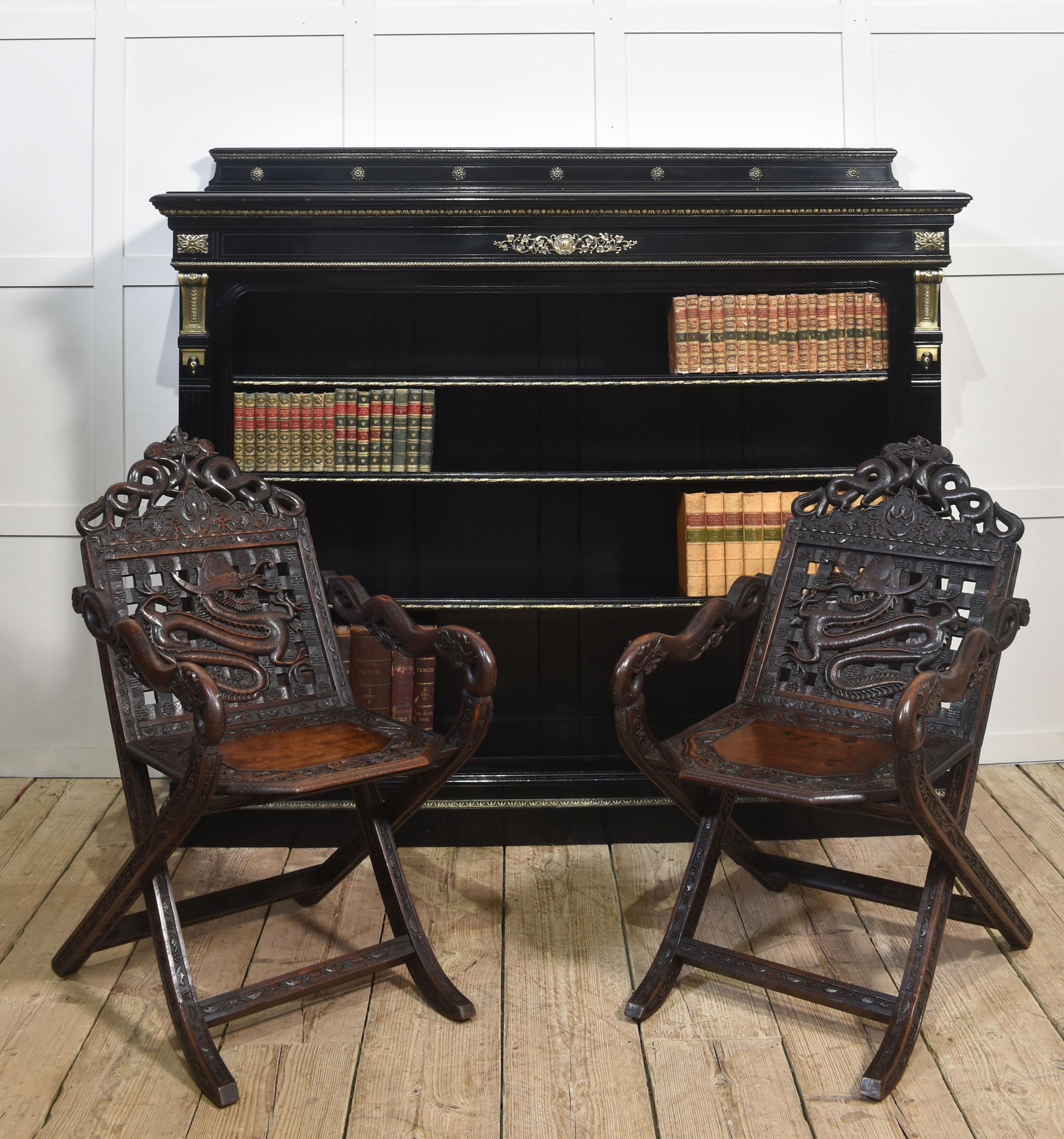 Librería abierta del siglo XIX, ebonizada y dorada, con decoración de follaje dorado. La parte superior es un cuarto de galería con borde moldurado, sobre un huevo dorado ornamentado y un diseño de roleos florales montado en el friso. Encima, tres