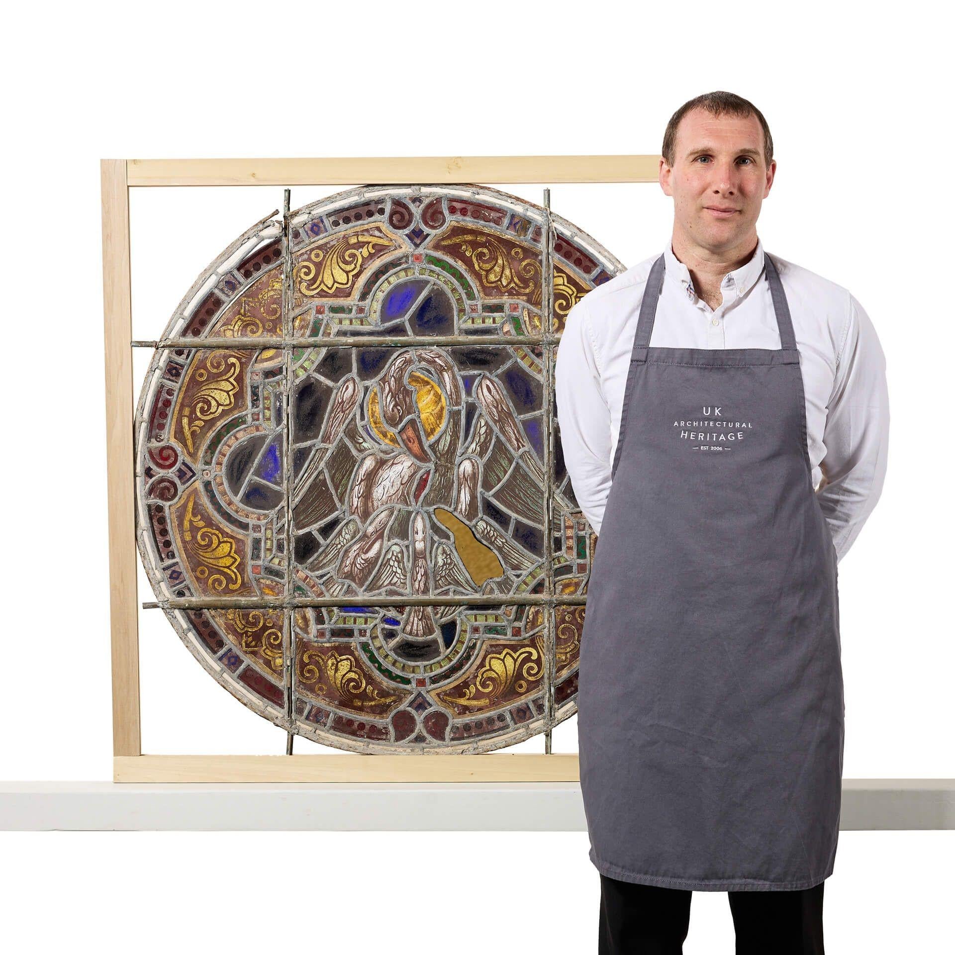 A large ø101cm antique ecclesiastical roundel stained glass panel depicting the pelican of piety. If looking for multiple, we are also selling other roundels in a very similar design.

This antique stained glass window features a vibrant array of