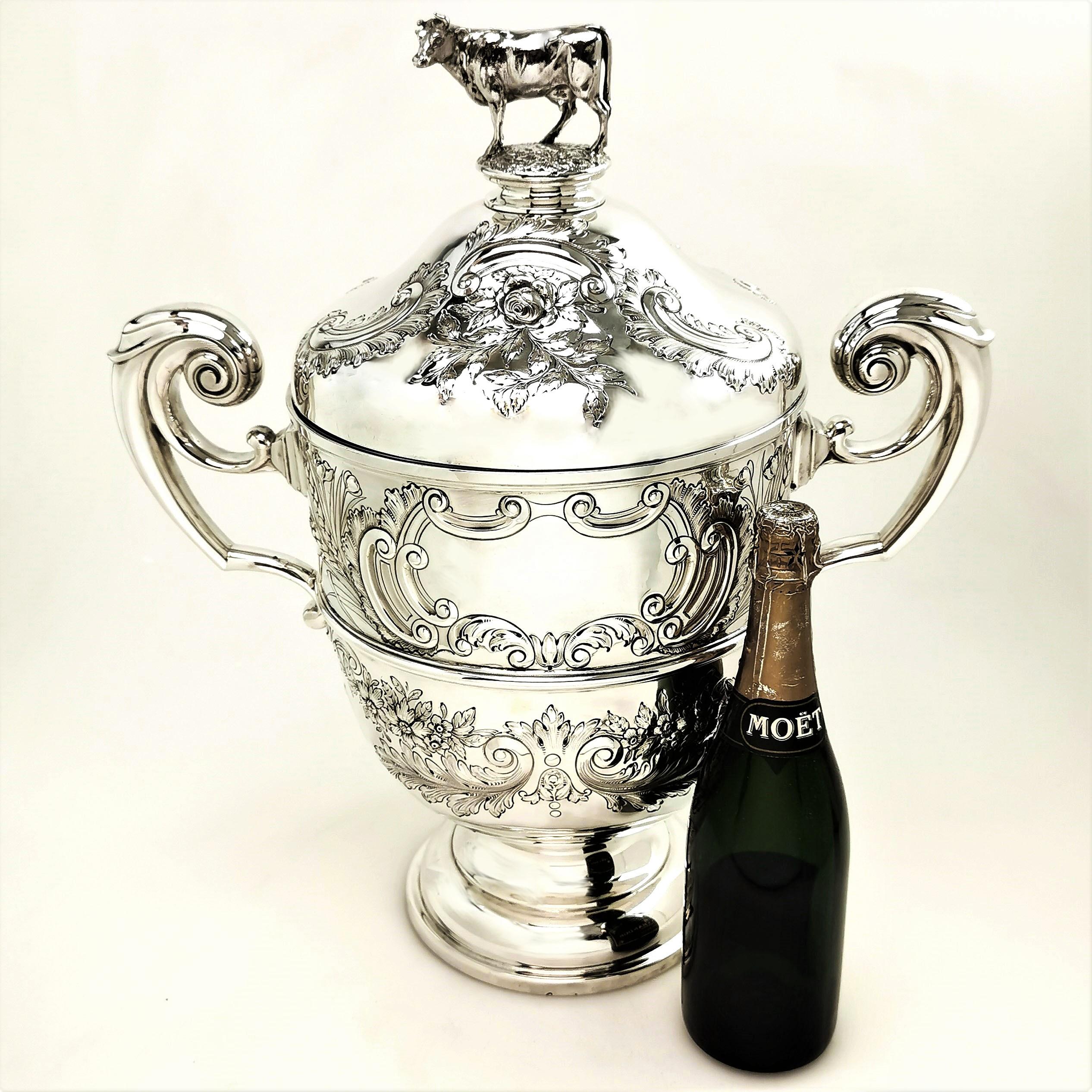 This enormous Antique Solid Silver Cup & Cover features a lovely chased design on the body and fitted lid. The lid has a cow figure as a finial and the Trophy has two extremely large scroll handles. The Cup has a blank cartouche on the one side
