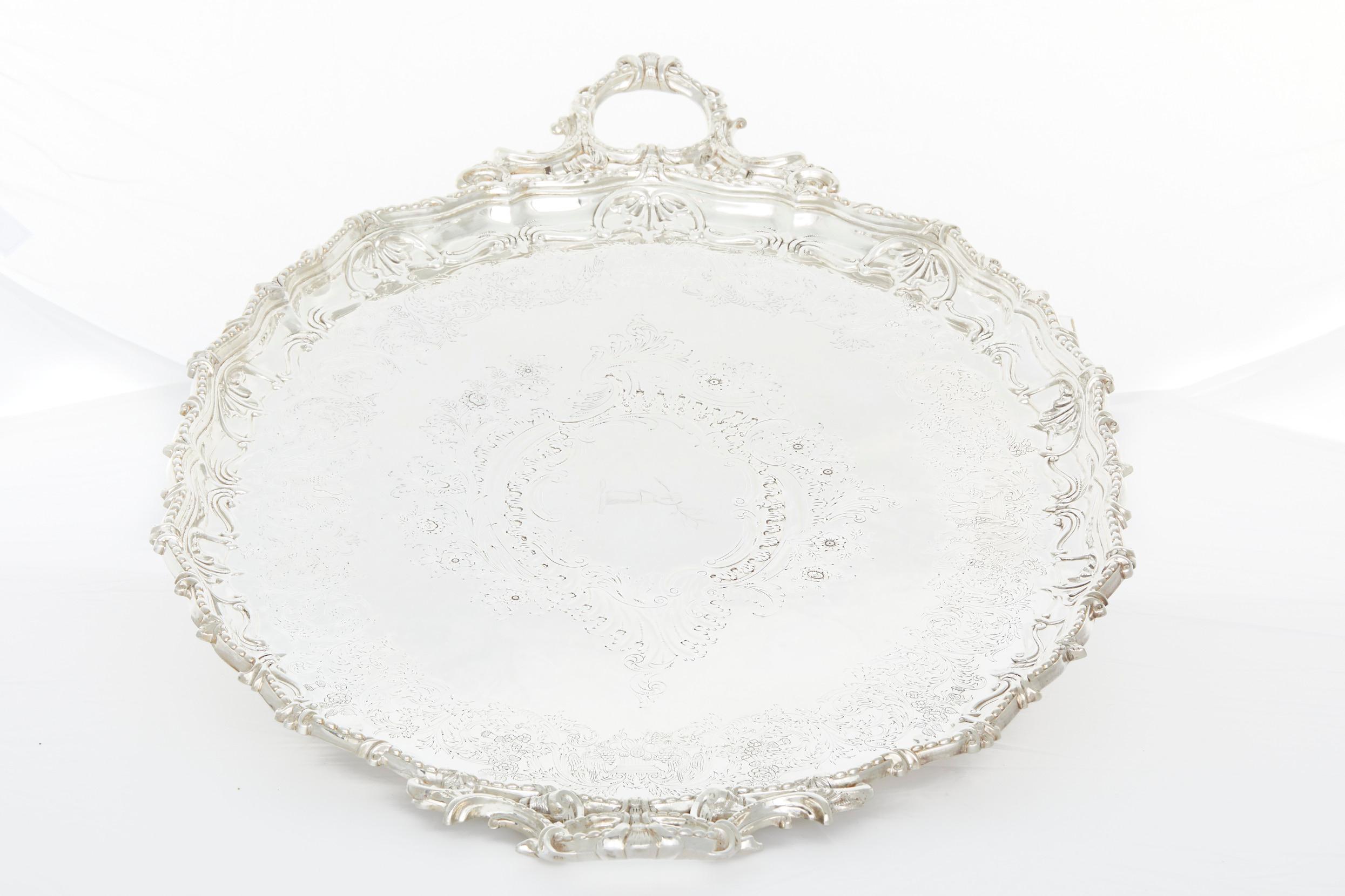 Large and heavy, Edwardian, Silver plated barware / tableware serving Tray . The tray features flat chased interior and exterior floral , scroll decoration to the body with a shaped shell and gadroon border, and an engraved crest and motto to the