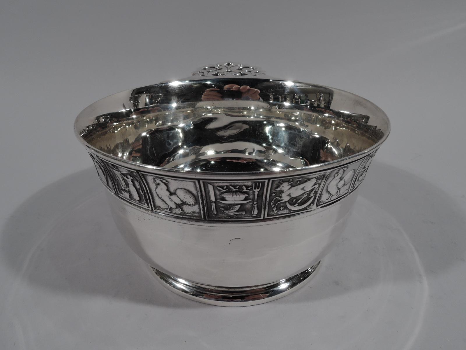 Large turn-of-the-century Edwardian sterling silver porringer. Made by Gorham in Providence. Deep and tapering bowl with raised foot and open scrolled handled. Rim border comprising square frames with low-relief pictogram-style representations of