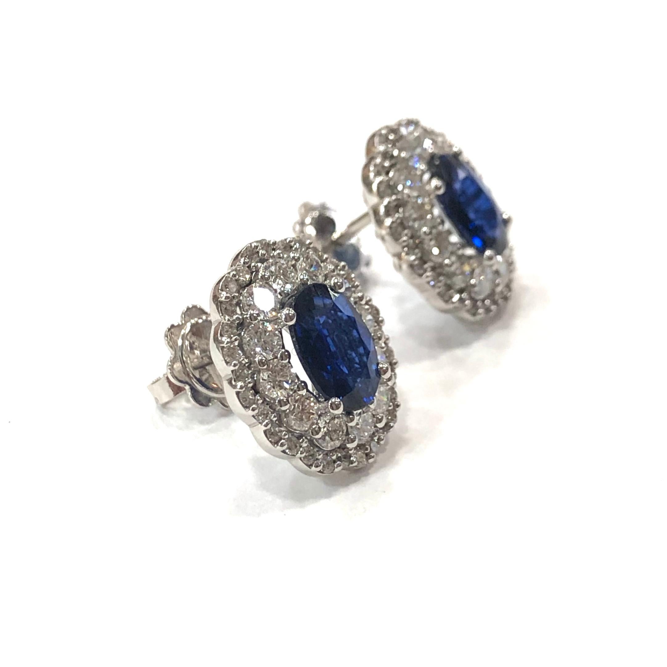 Large Edwardian Style Sapphire and Diamond Cluster Ear Studs. Each set with one central large 7 x 5mm blue untreated natural sapphire in a four claw setting, surrounded by two rows of round brilliant cut Diamonds in a filigree style design. With a