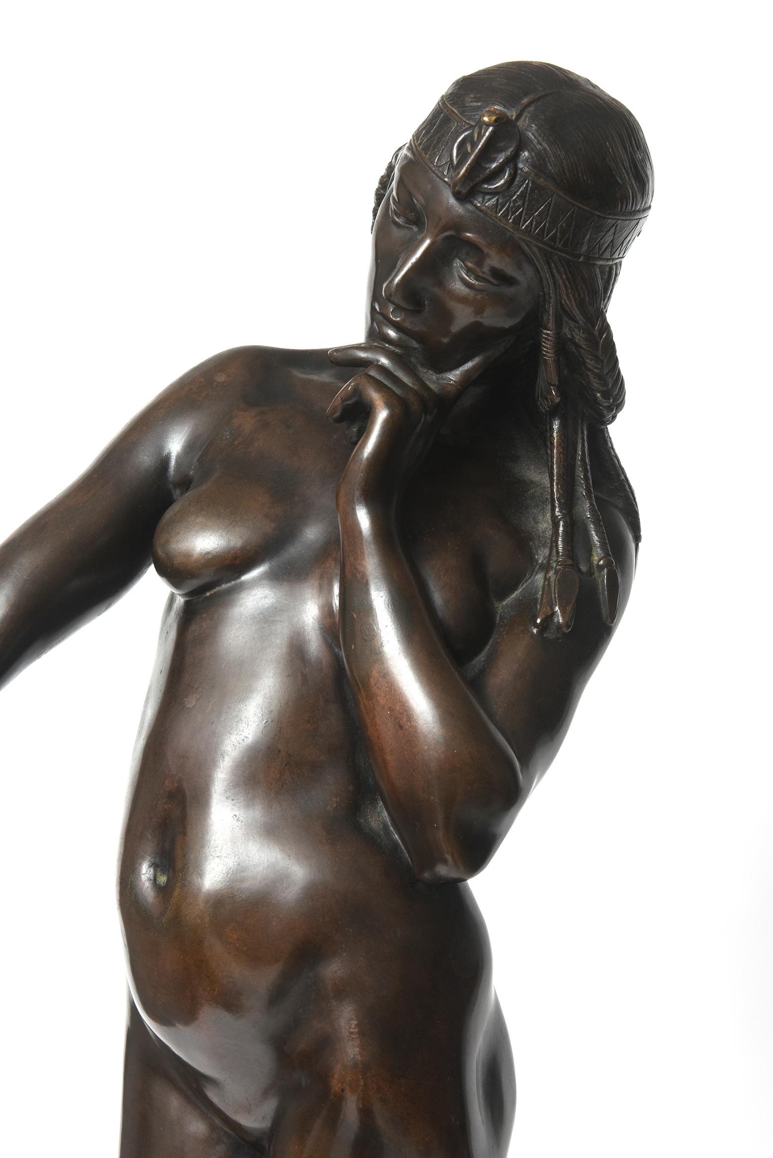 Striking bronze sculpture of a nude Cleopatra looking at herself in wonder in a mirror. She's wearing a cobra snake head band piece and her hair in braids. She is standing on a highly decorated stool. The front section of the stool is gilded and has