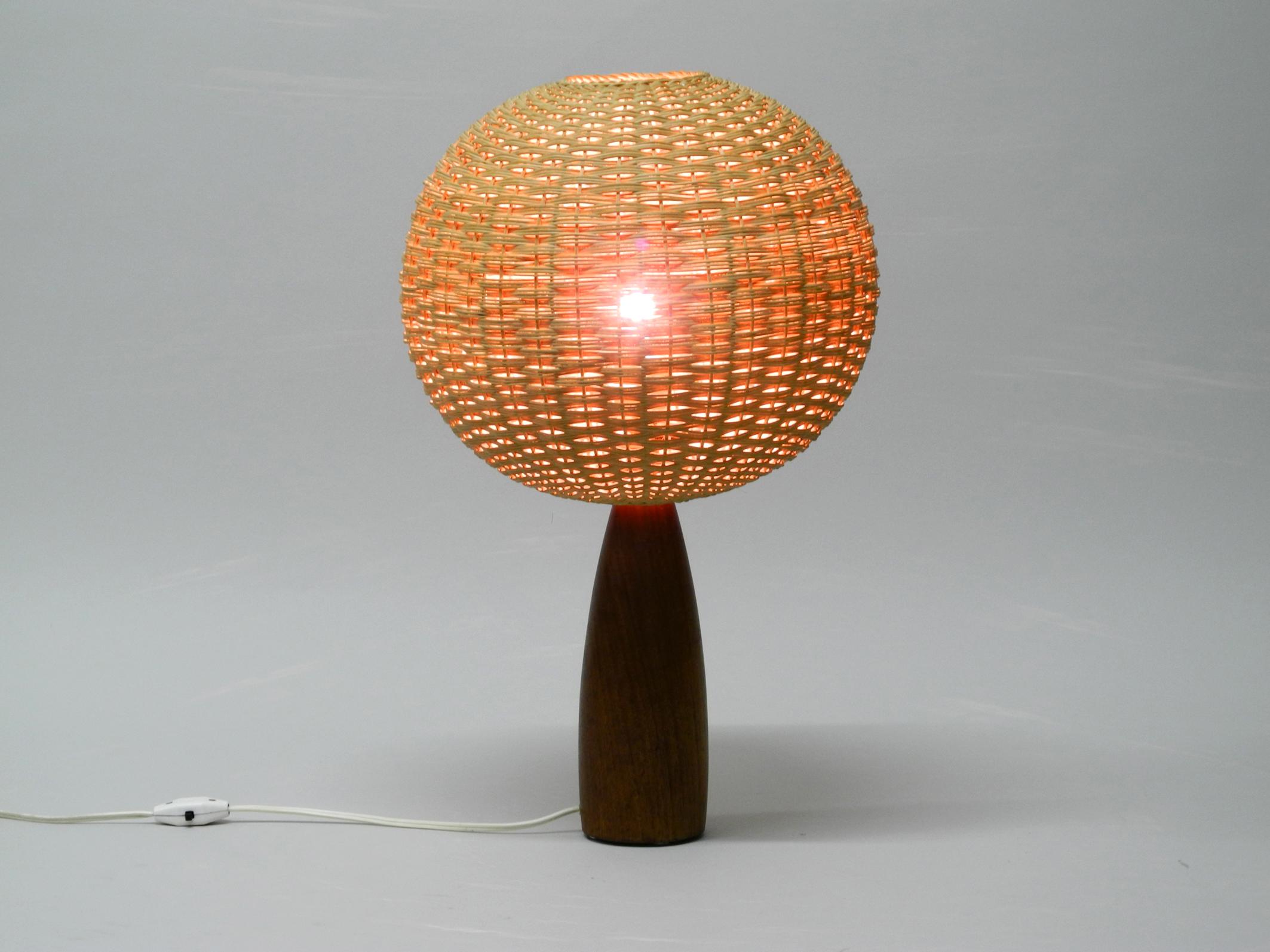 Large elegant 1960s teak table lamp with large wicker lampshade. 
Great 1960s design in very good vintage condition. From a scandinavian production. 
Most likely from Denmark.
The spherical basket lampshade is made of fine wicker. 
Creates a