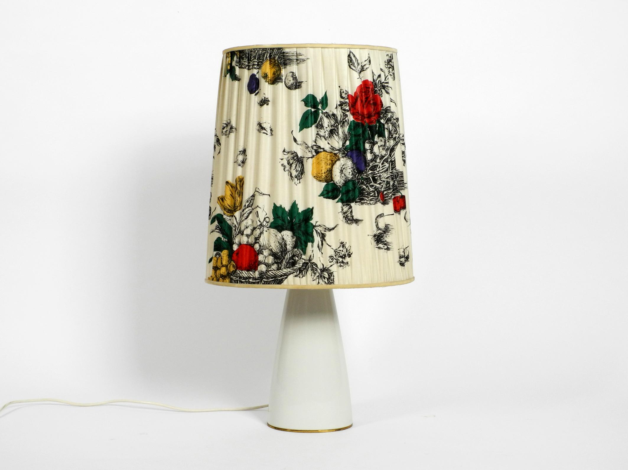 Large elegant 1960s KPM table lamp with porcelain foot and pleated silk lampshade.
Manufacturer is Königliche Porzellan-Manufaktur (KPM) Berlin. 
Very elegant and high quality design.
The lamp foot is made of shiny white porcelain.
The foot, the