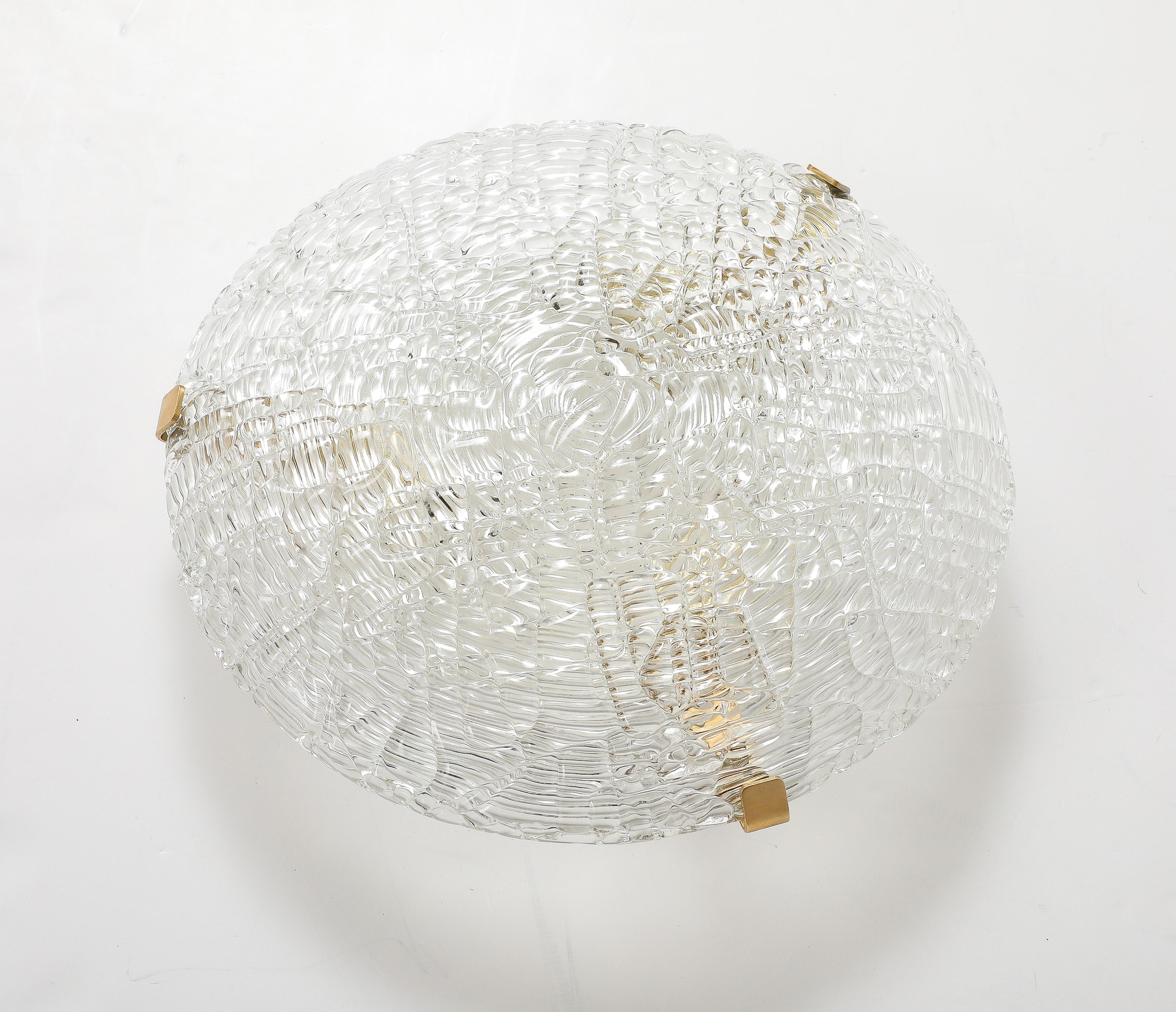 Magnifique luminaire encastré en verre et laiton des années 1960 par JT Kalmar.
Le grand verre en forme de dôme présente une merveilleuse texture à effet d'ondulation de l'eau sur les deux côtés du verre et est soutenu par 3 clips en laiton poli