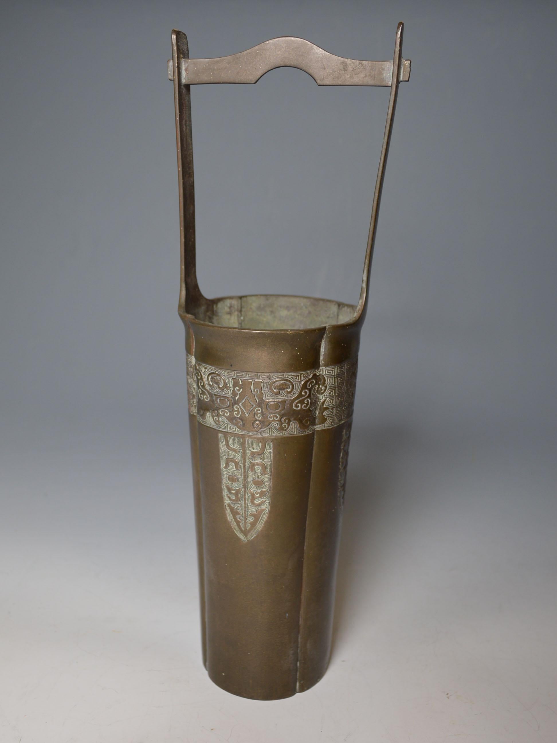 A tall bronze vase in the shape of a water well pot with archaic design patterns
This type tall slender elegant shaped vase used for flower arrangement in Japanese traditional tea ceremony.
Period: Japan, Showa period, late 19th-early 20th