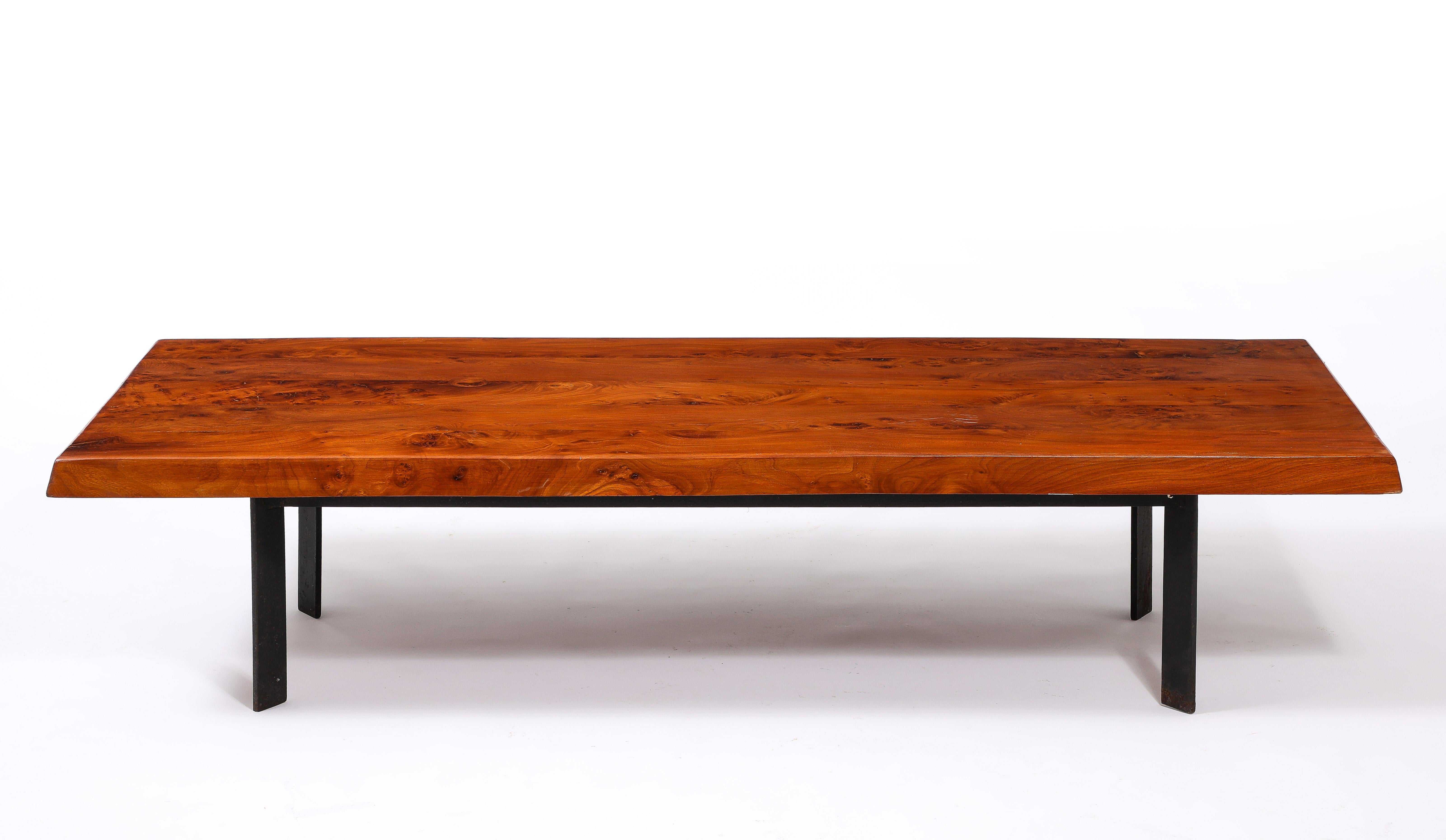 Le plateau en trapèze en orme massif repose sur des pieds inclinés en acier. La table présente des éléments de design que l'on retrouve dans les productions Chapo et Lebbe.
