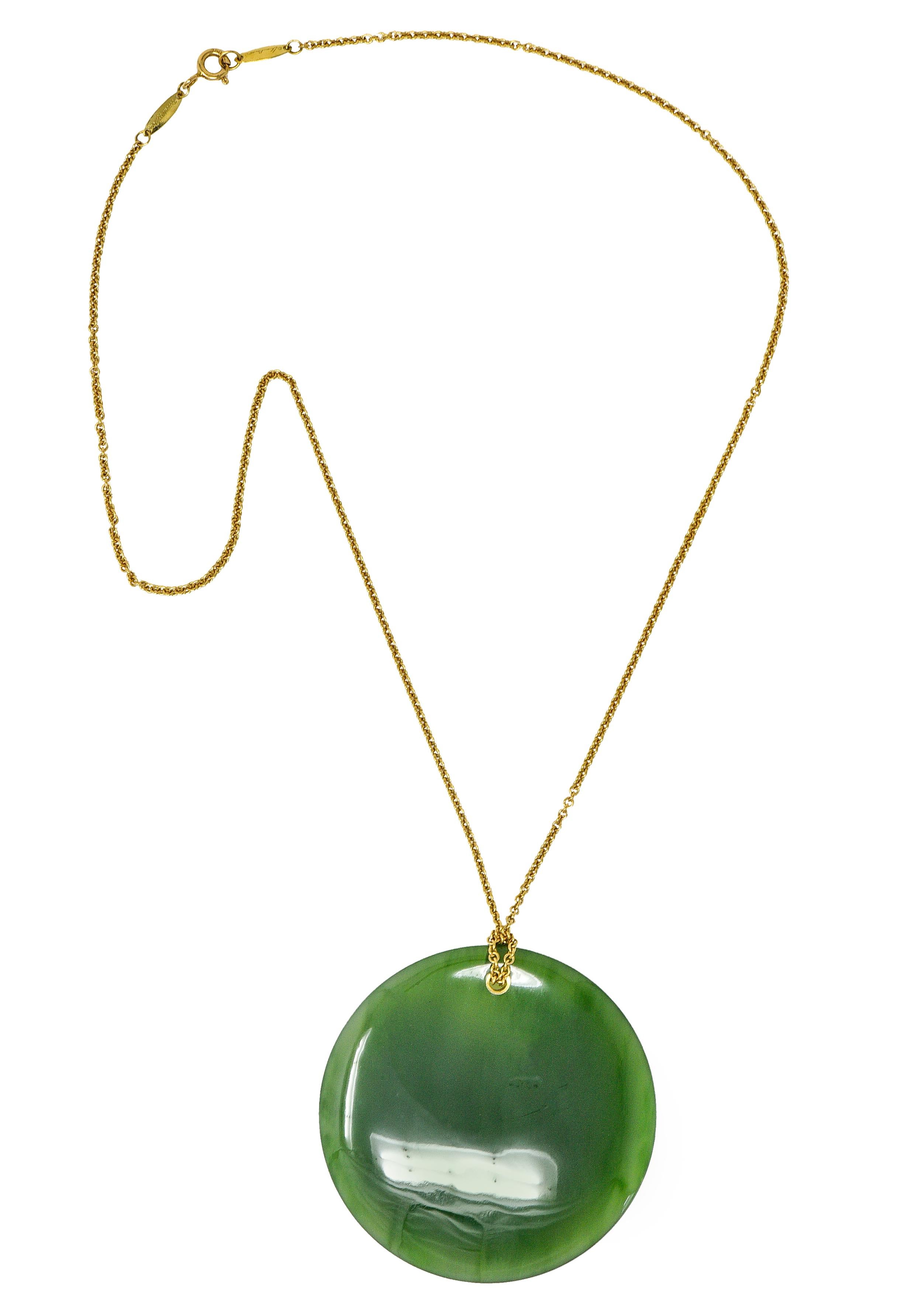 Cable chain necklace is knotted through a substantial Touchstone pendant. Circular with a subtle concave impressions. Translucent yellowish green in color with mild dark green mottling. Completed by a spring ring clasp with logo links. Stamped 750