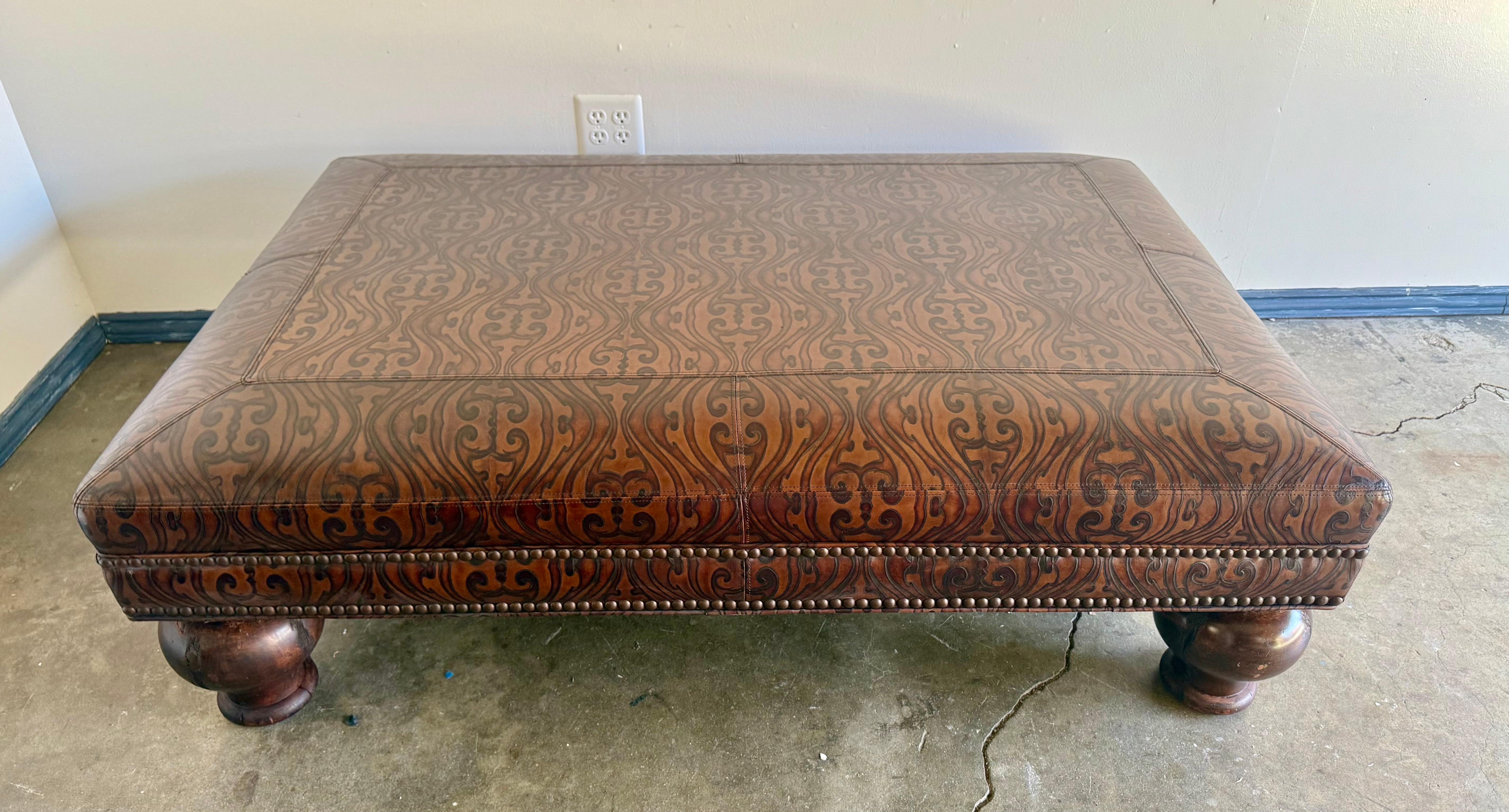 A substantial rectangular ottoman upholstered in richly embossed leather, mid-20th century. The warm brown leather features an elegant damask-inspired pattern with subtle tonal variation, giving depth and character to the surface. The tailored