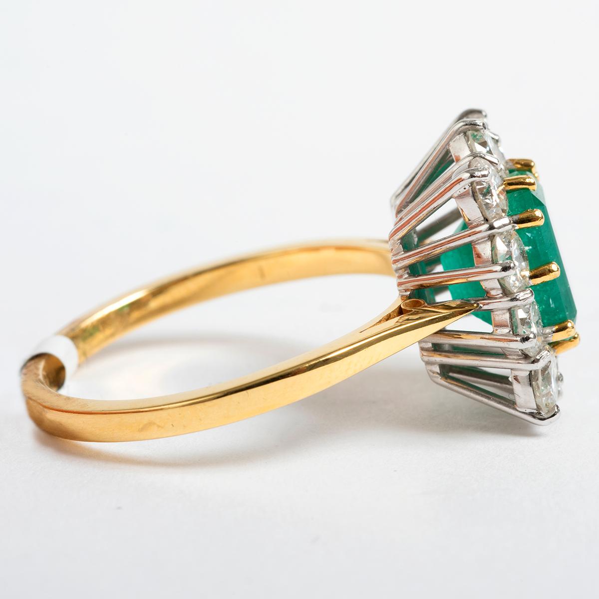 This classically designed ring from the 1960's showcases a generous emerald with surrounding diamonds. This ring is set in 18k Yellow Gold. Diamonds set in est 1.61ct and emerald est 1.97ct in weight. A true statement piece this ring comes in UK