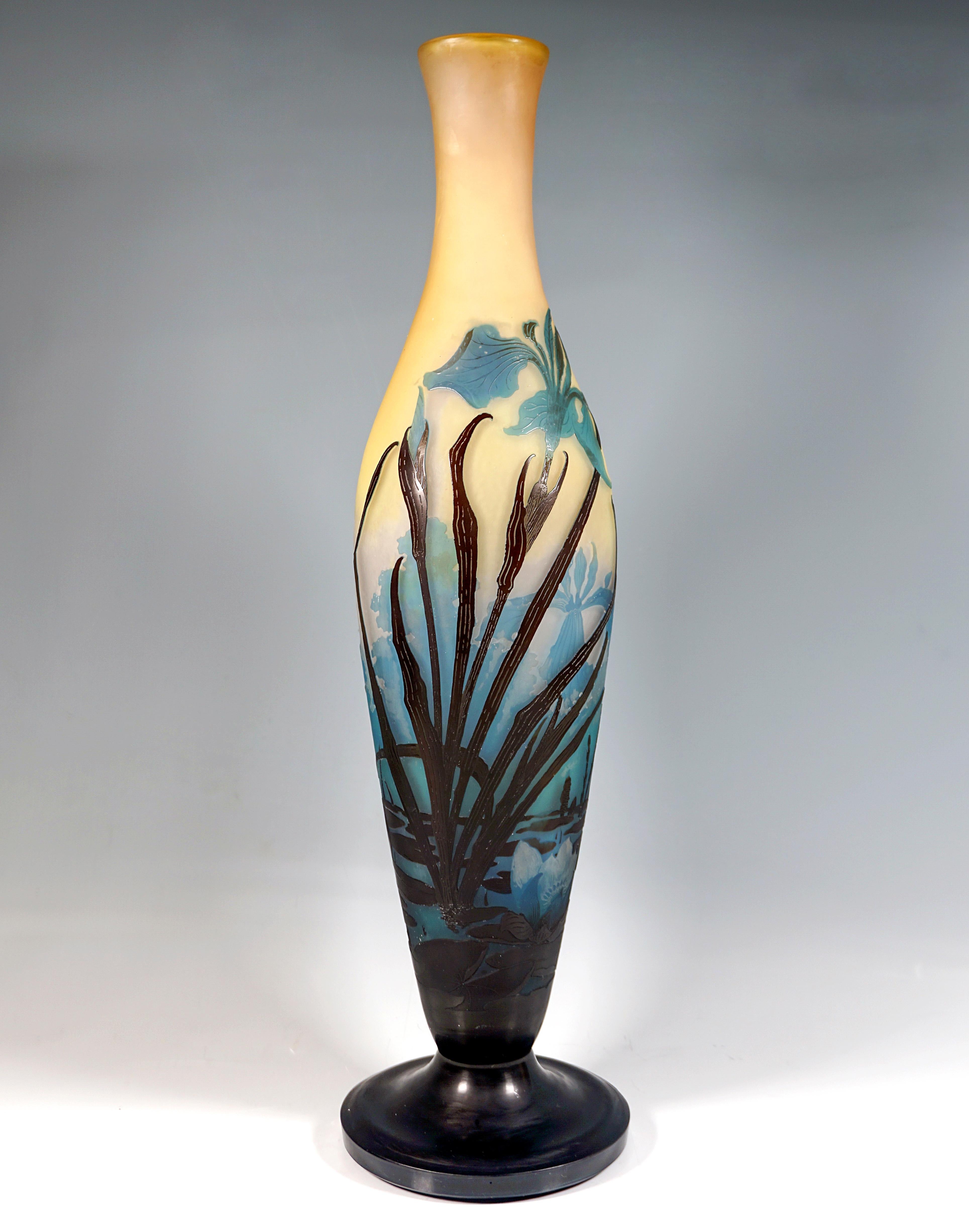 Slender baluster-shaped vase body on a separate base, widening conically towards the top and then narrowing again to form a slender neck with a flared mouth rim, colorless glass with yellow-orange color powder inclusions in the upper area, overlays