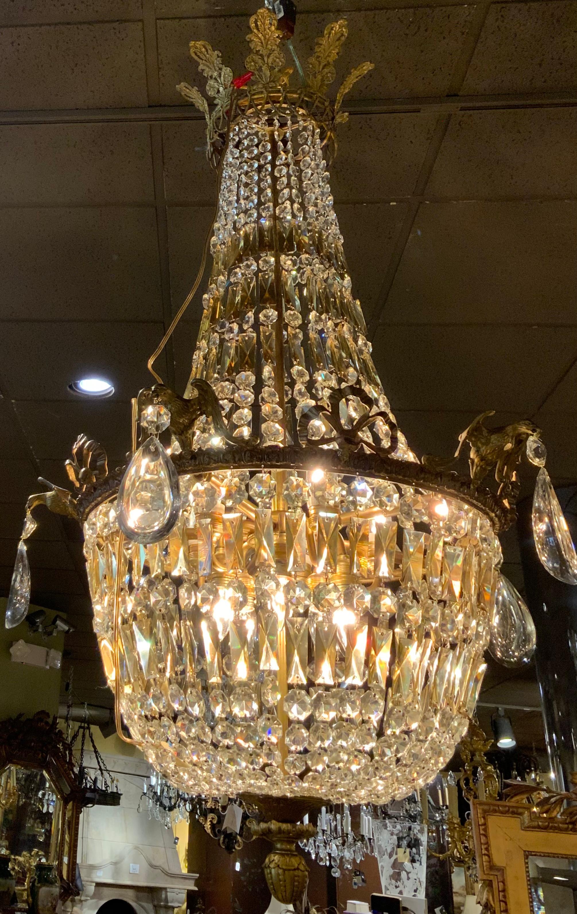 Large and impressive chandelier with both clear and
Amber color crystal. The Top piece is in the shape of a crown.
The perimeter of the bowl has a rim of antique bronze
Which is decorated with eagles holding a large crystal.
In between the eagles