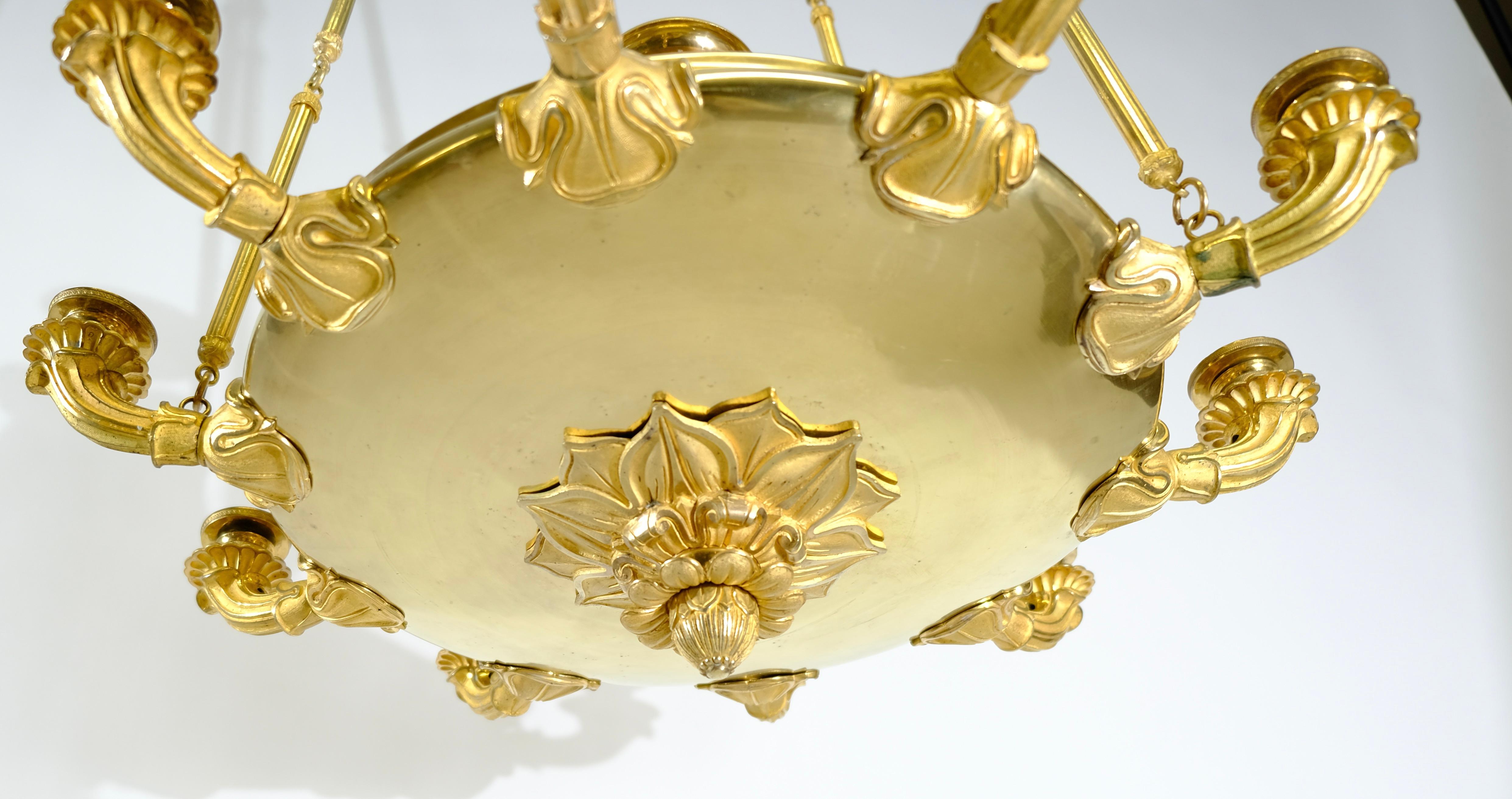 A unusually large chandelier with a beautiful design. The chains that holds the chandelier are of an interesting shape with grooved pipes and rings. The pressure-turned saucer-like central piece holds the ten cast gilt bronze arms with