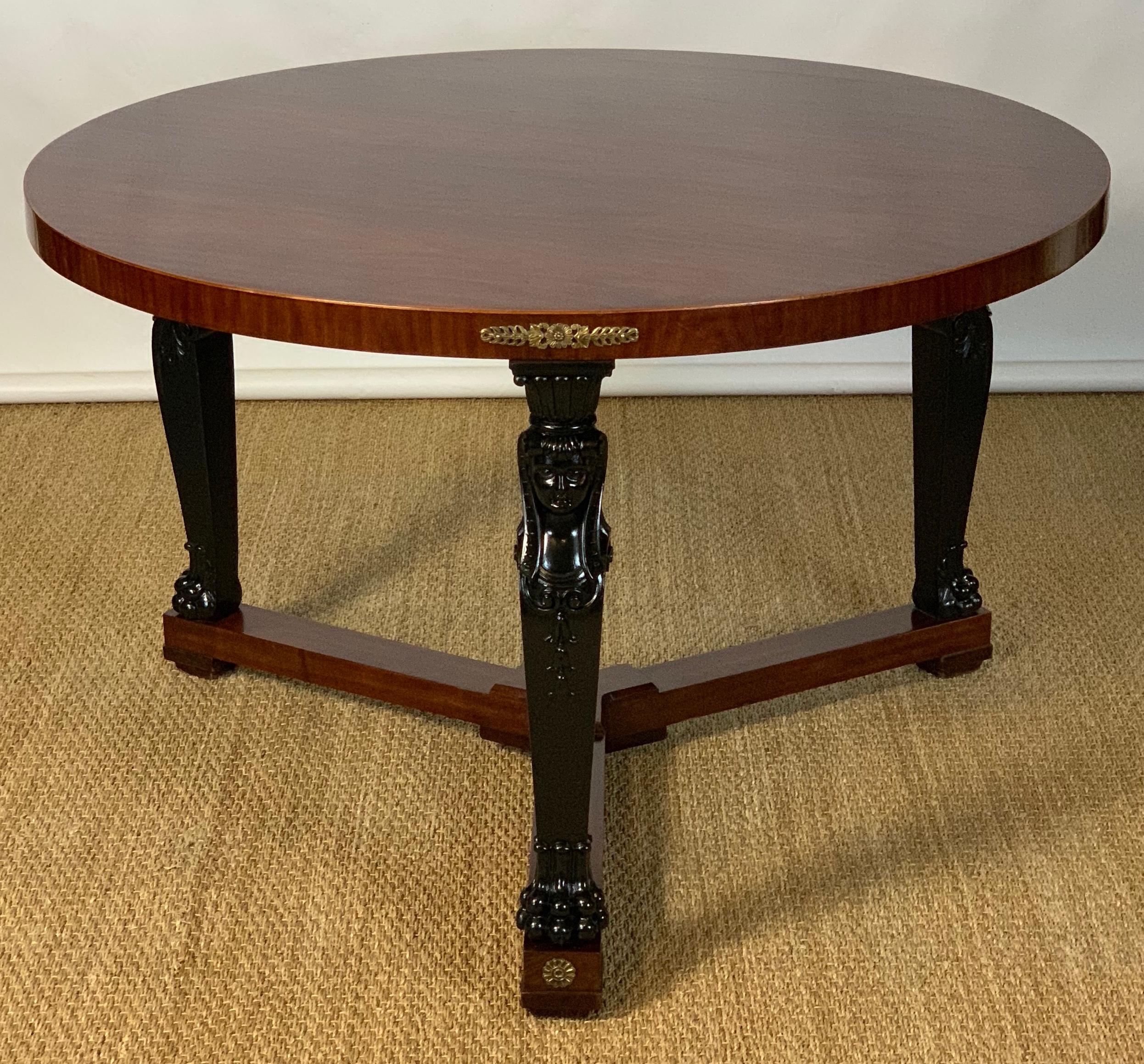 A large and elegant mid-20th century French Empire style mahogany center or library table accented with ebonized caryatid legs and ormolu mounts.