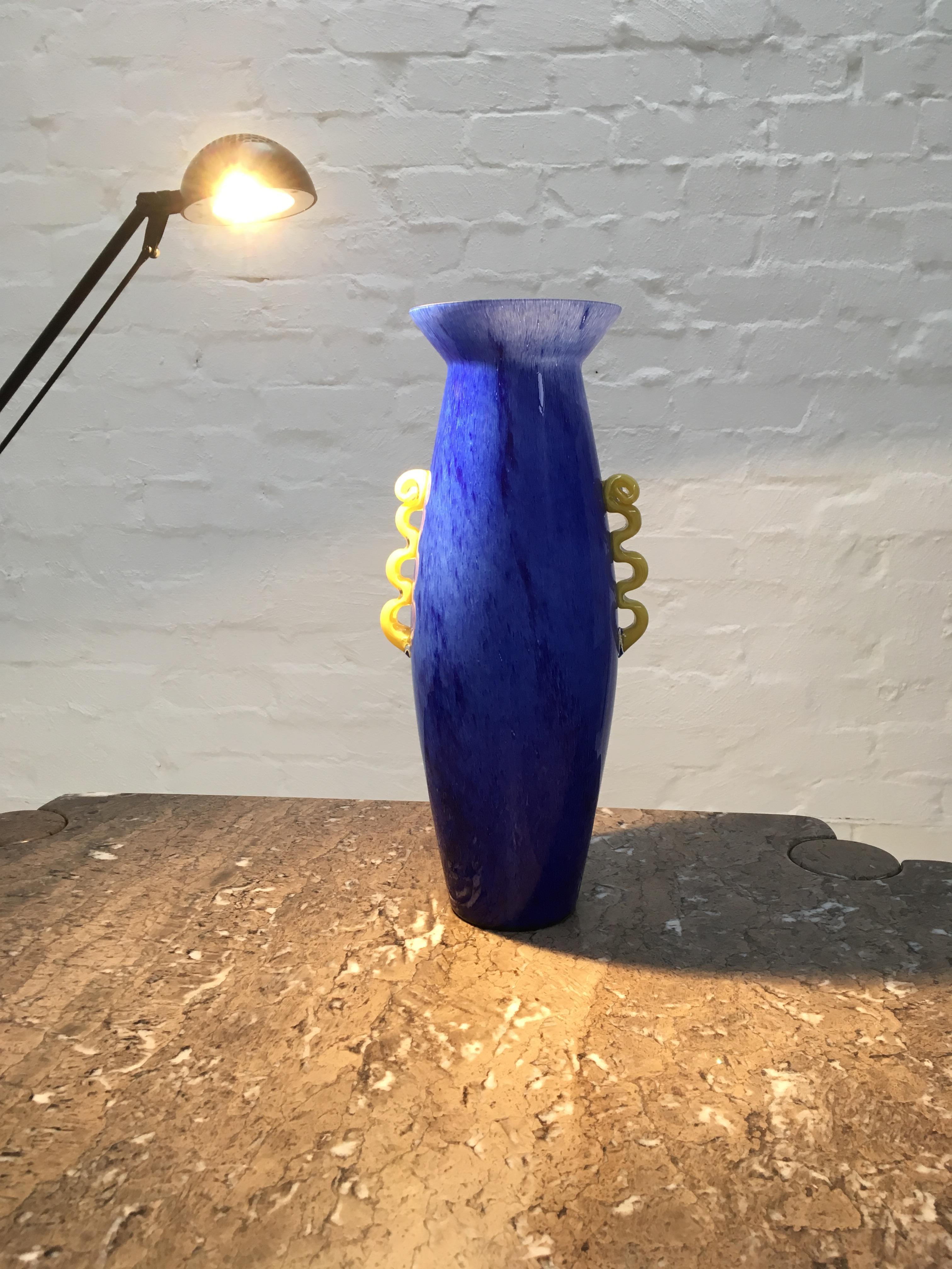 A magnificent cased glass Amphora made in the Empoli region of Italy. 

This huge vase is strongly influenced by the Memphis Milano design movement. 

The angled lip, speckled cobalt blue exterior and yellow ‘threaded’ handles are a Postmodern