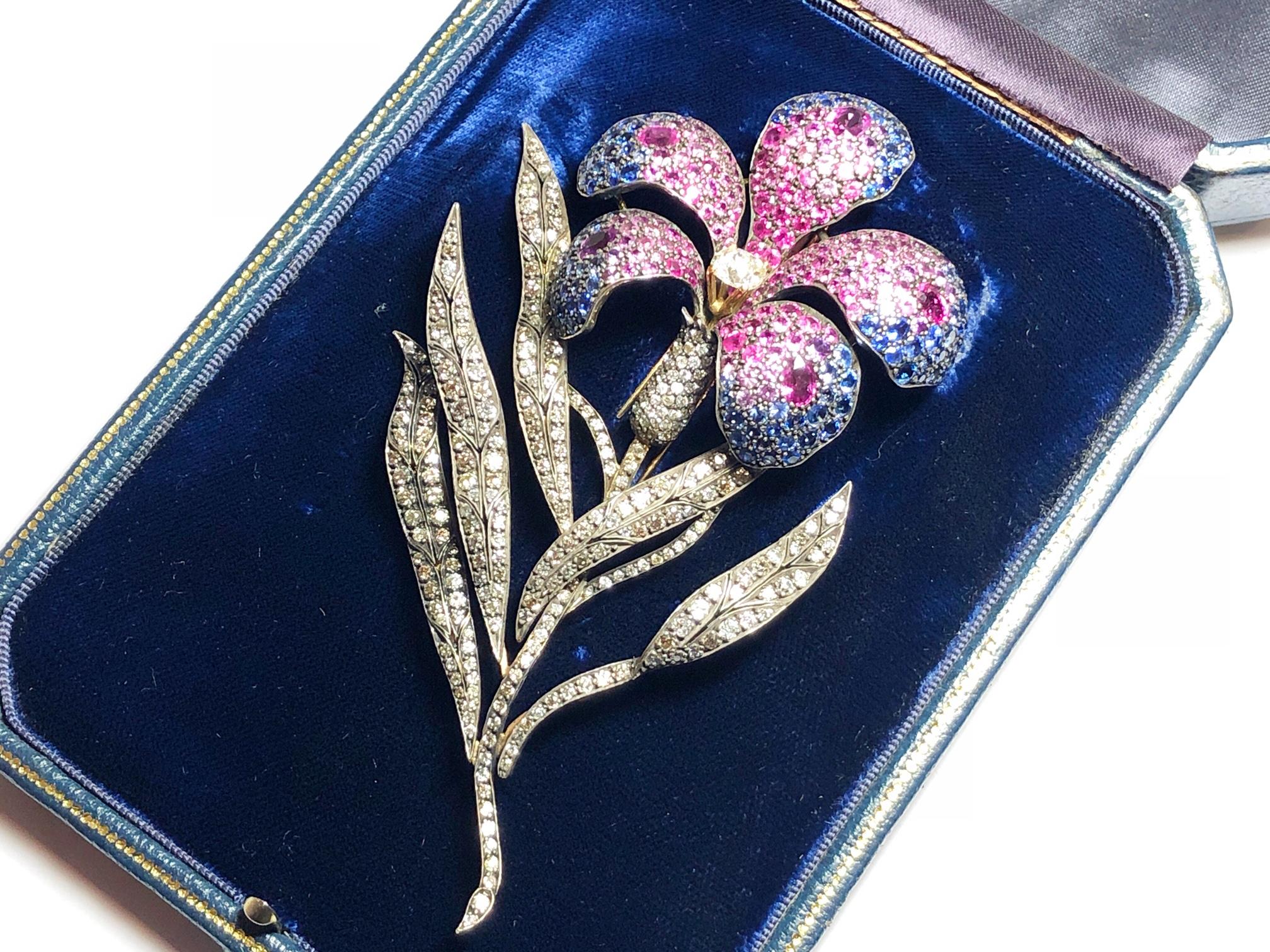 Moira Sapphire and enamel carnation flower brooch, set with blue and pink shaded sapphires and with old-cut diamond set leaves, mounted in silver upon gold