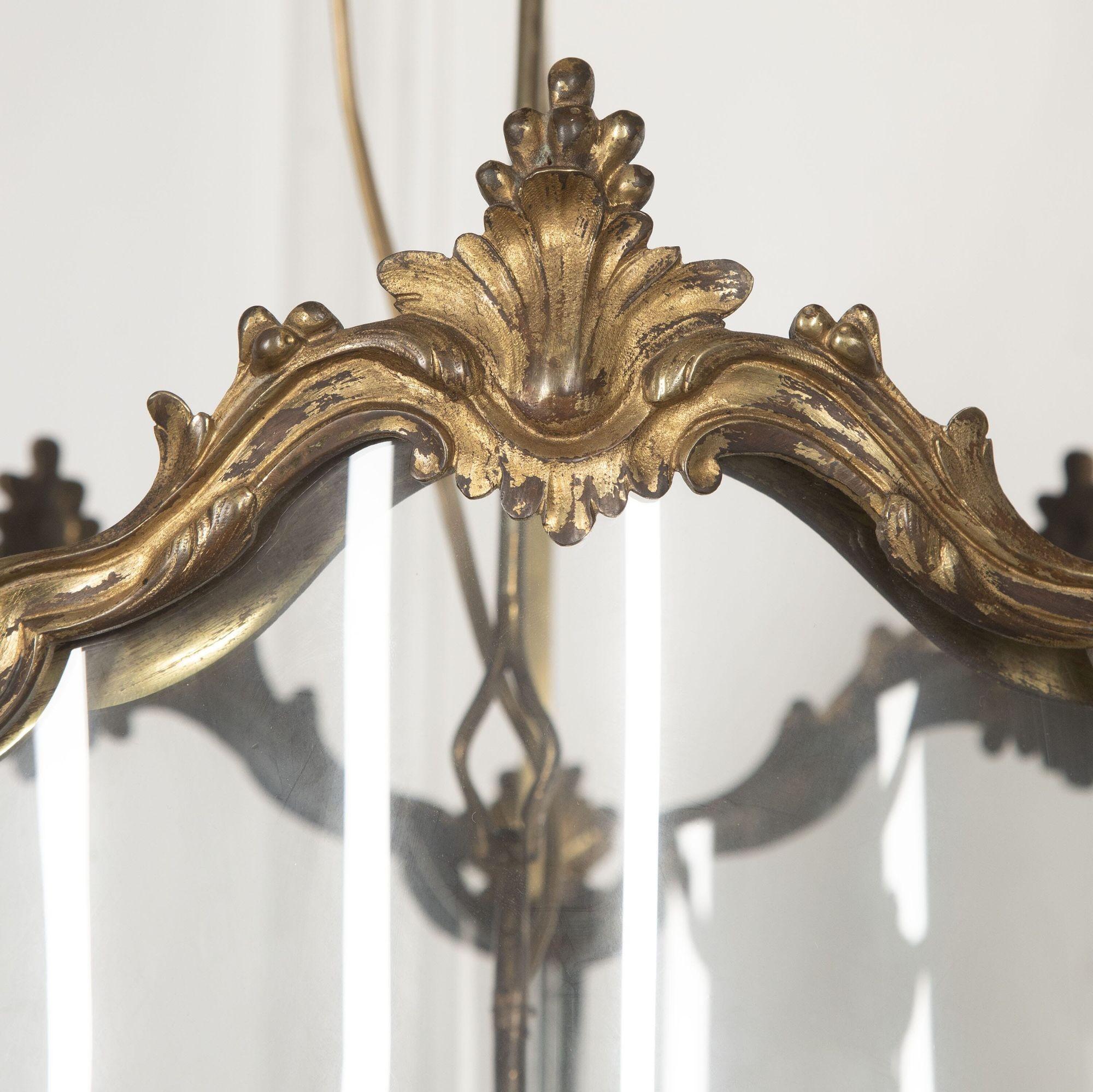 Large 18th century English gilt bronze hall lantern with a finely cast frame of serpentine form.
The curved glass panels are headed by chased acanthus leaves and sit on leaf and berry finials.
The original four-light hanging candelabra with