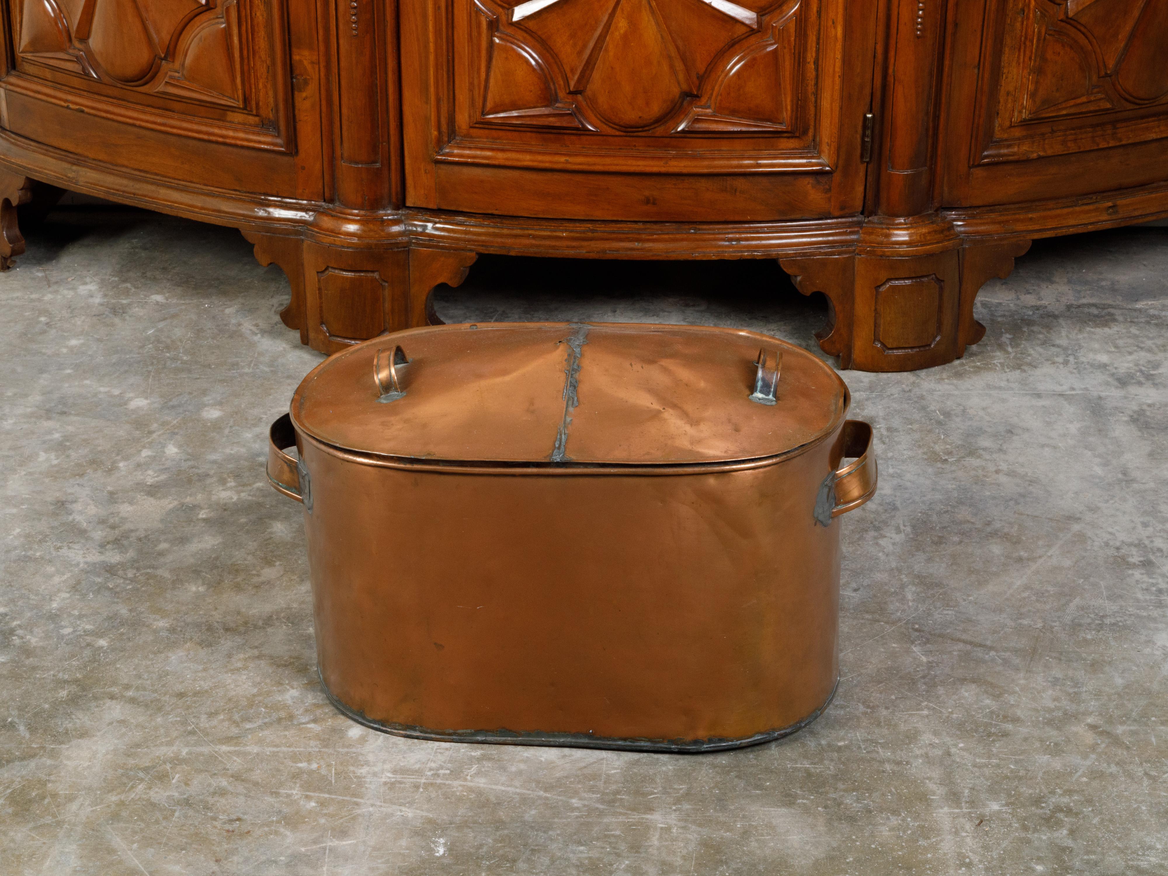 A large English copper braising pan from the mid 20th century, with lateral and top handles and weathered patina. Created in England during the second quarter of the 20th century, this large braising pan used to cook meat and vegetables will make