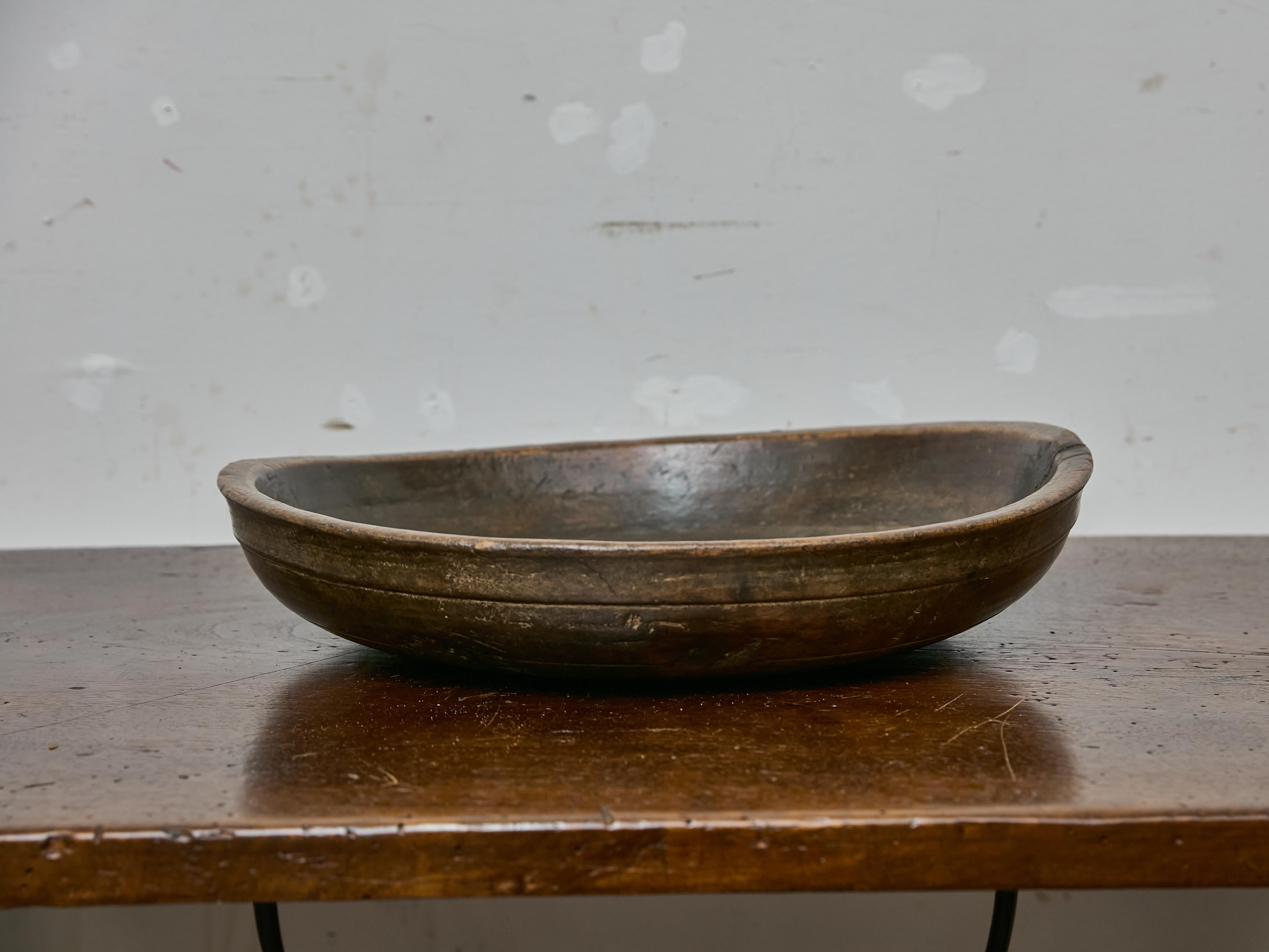 This generously sized English walnut bowl dates to the 19th century and showcases the warm, mellow patina developed from over a century of use. Hand-carved from a single piece of walnut, the form is broad and subtly oval, with softly sloped walls