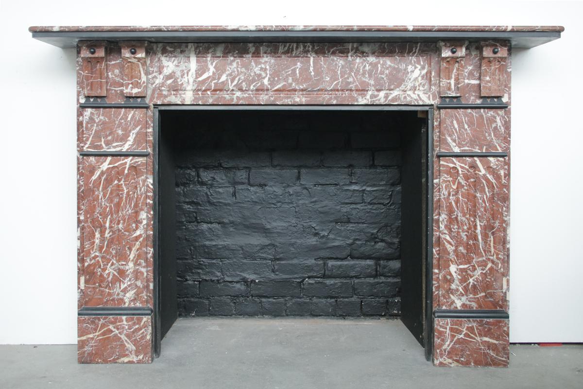 A large late Victorian fireplace surround in well figured Rouge marble. The stepped shelf is Belgian black marble underside is supported by twin fluted corbels and applied marble bosses. The jambs are also fluted and decorated with further Belgian