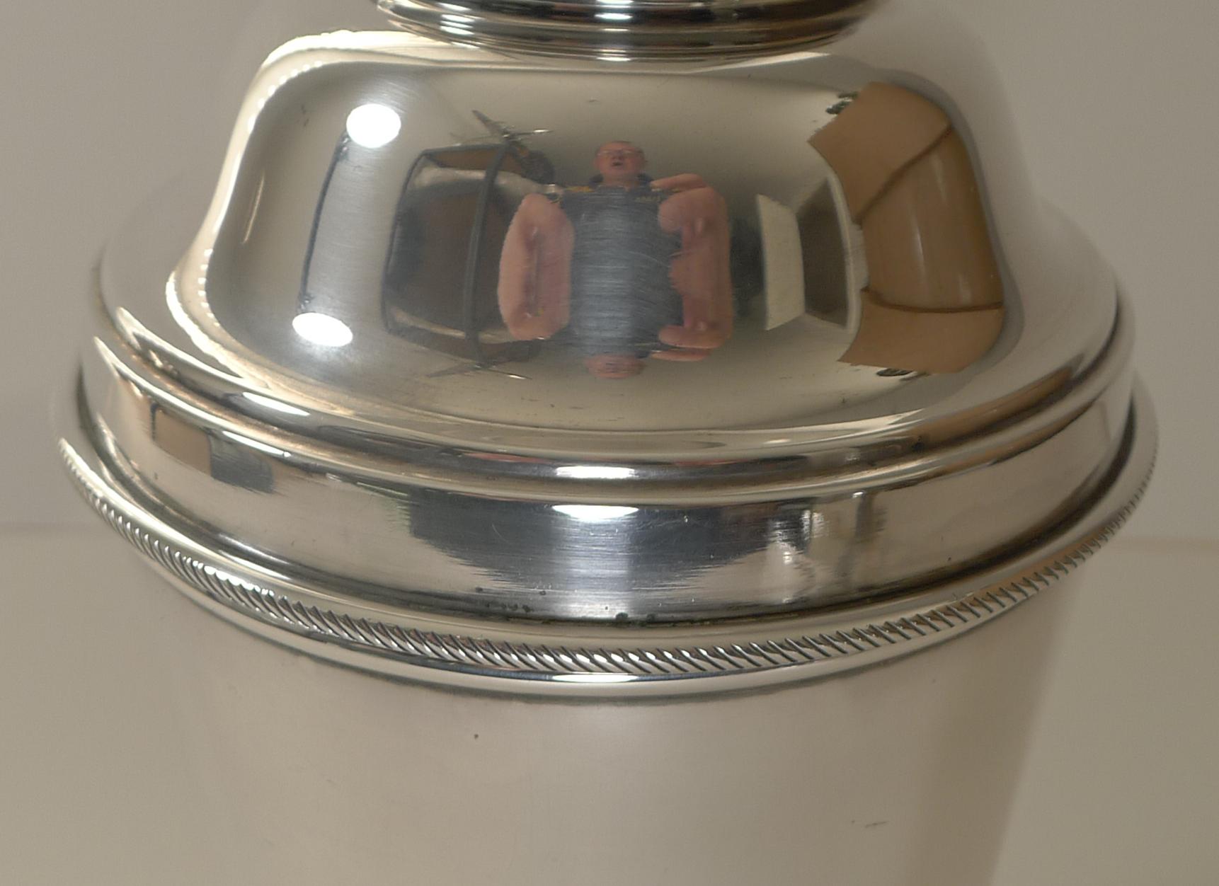 A large Art Deco silver plated cocktail shaker by the top notch silversmith, James Dixon and Sons. 

The top section, once removed, reveals the integral ice breaker / crusher in the lid; always highly sought-after.

The underside is fully marked