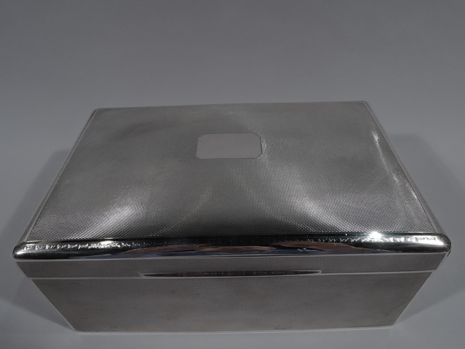 Large Art Deco sterling silver box. Made by Walker & Hall in Sheffield, circa 1930. Rectangular with curved, hinged, and tabbed cover. Dense engine-turned ornament in plain frames. Cover top has central and chamfered rectangular frame (vacant);