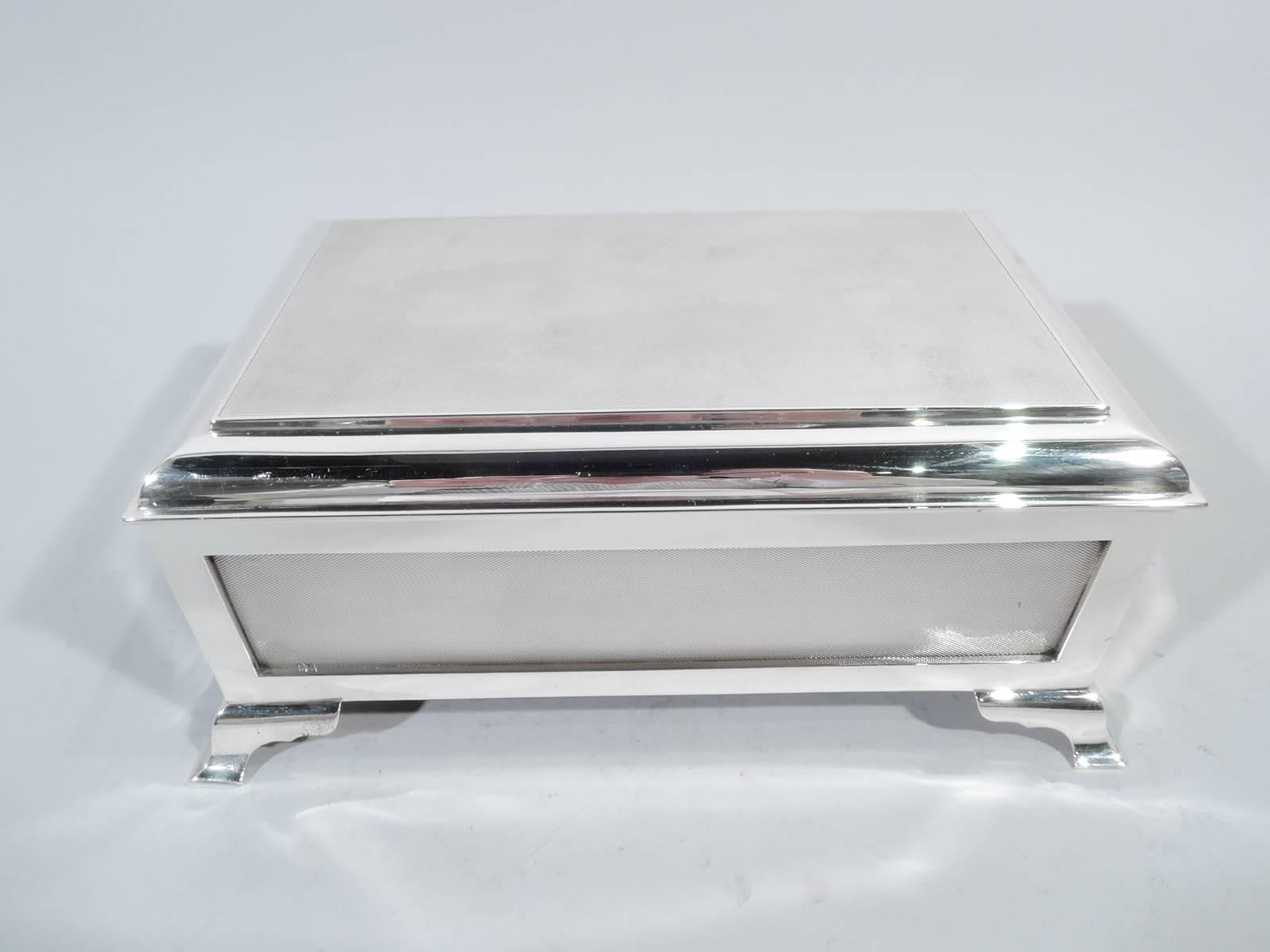 George VI sterling silver casket box. Made by Richard Comyns in London in 1946. Rectangular with straight sides and corner bracket supports. Paneled and engine-turned sides. Cover hinged and raised with engine-turned top. Box interior cedar-lined