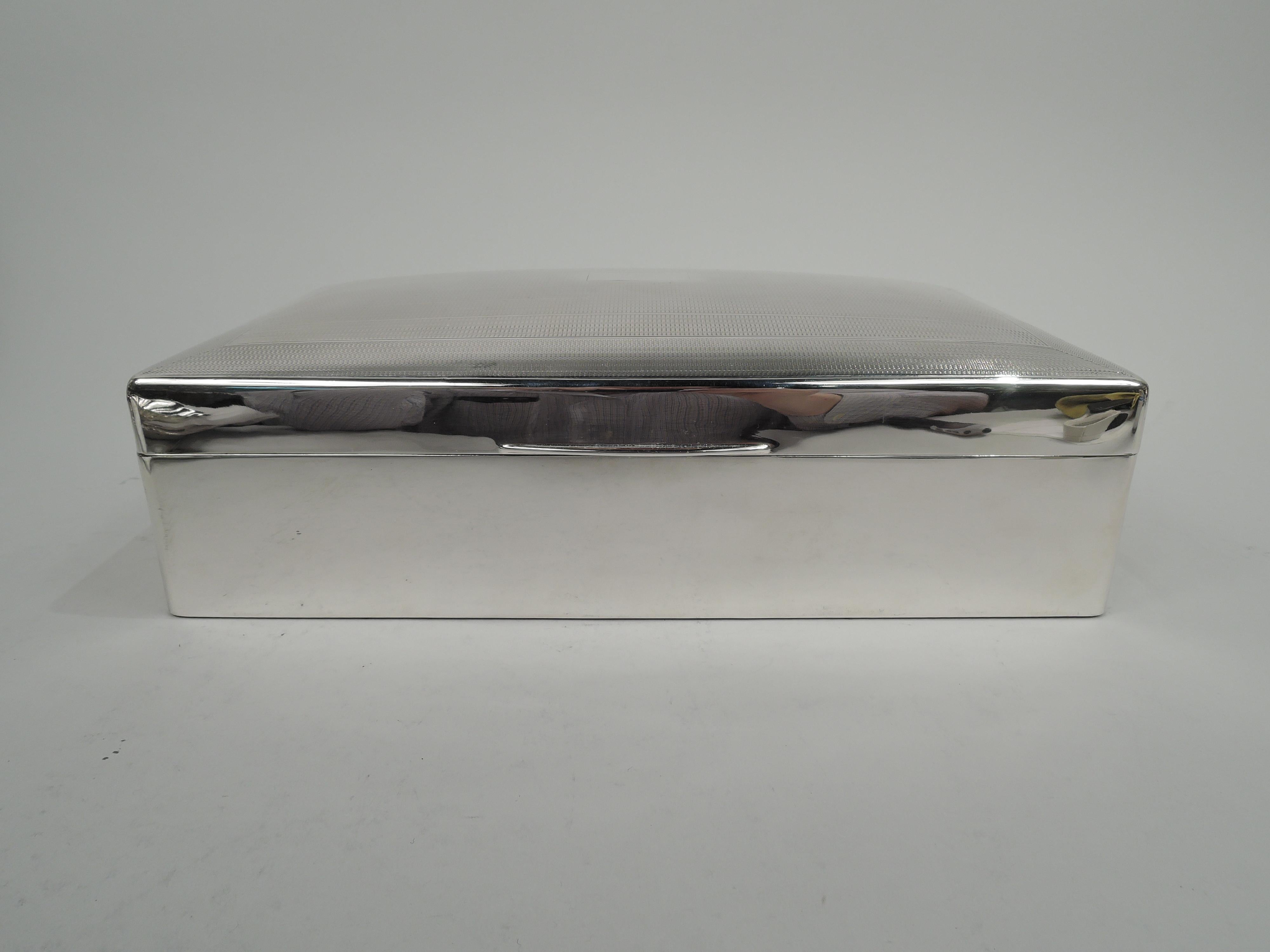 George V sterling silver cigar box. Made by Deakin & Francis Ltd in Birmingham in 1927. Rectangular with straight sides and curved corners. Cover hinged with tapering tab; top gently curved with engine-turned horizontal bands and wraparound borders;