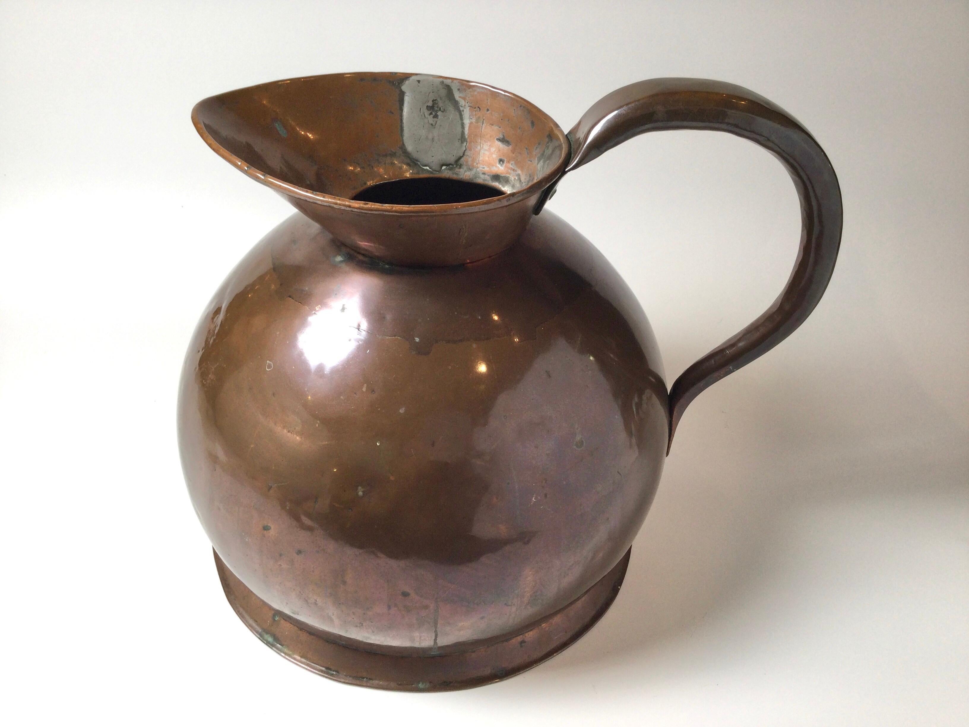 A large handmade copper pitcher, England Circa 1890. Note the the seams and welds with the old patination. 13 inches tall 17 inces deep with handle, 44 inches all the way around circumference.
