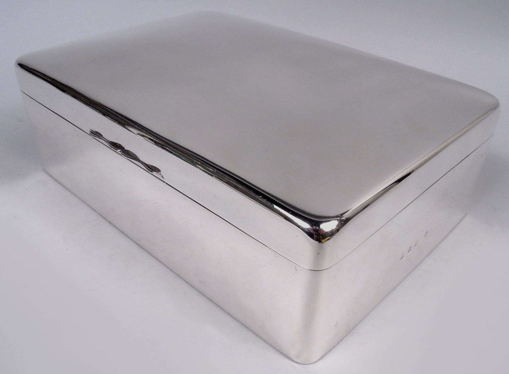 Edwardian sterling silver box. Made by A & J Zimmerman in Birmingham in 1902. Rectangular with straight sides and curved corners. Cover hinged with gently curved top and scrolled tab. Box interior cedar lined. Cover interior gilt washed. Bottom